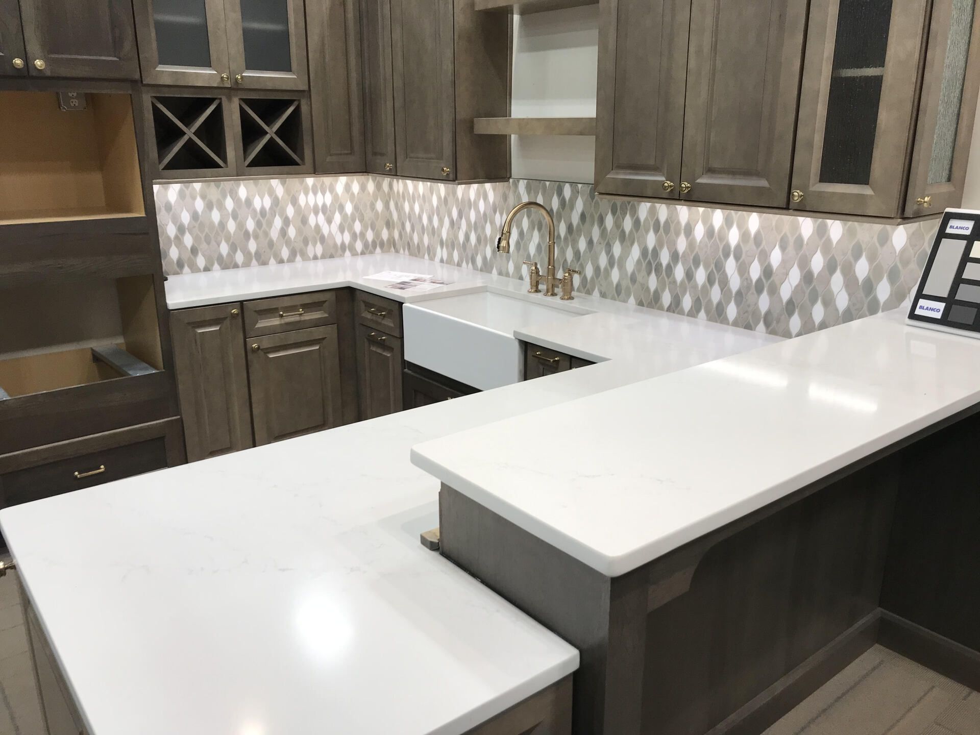 A kitchen with white counter tops and gray cabinets