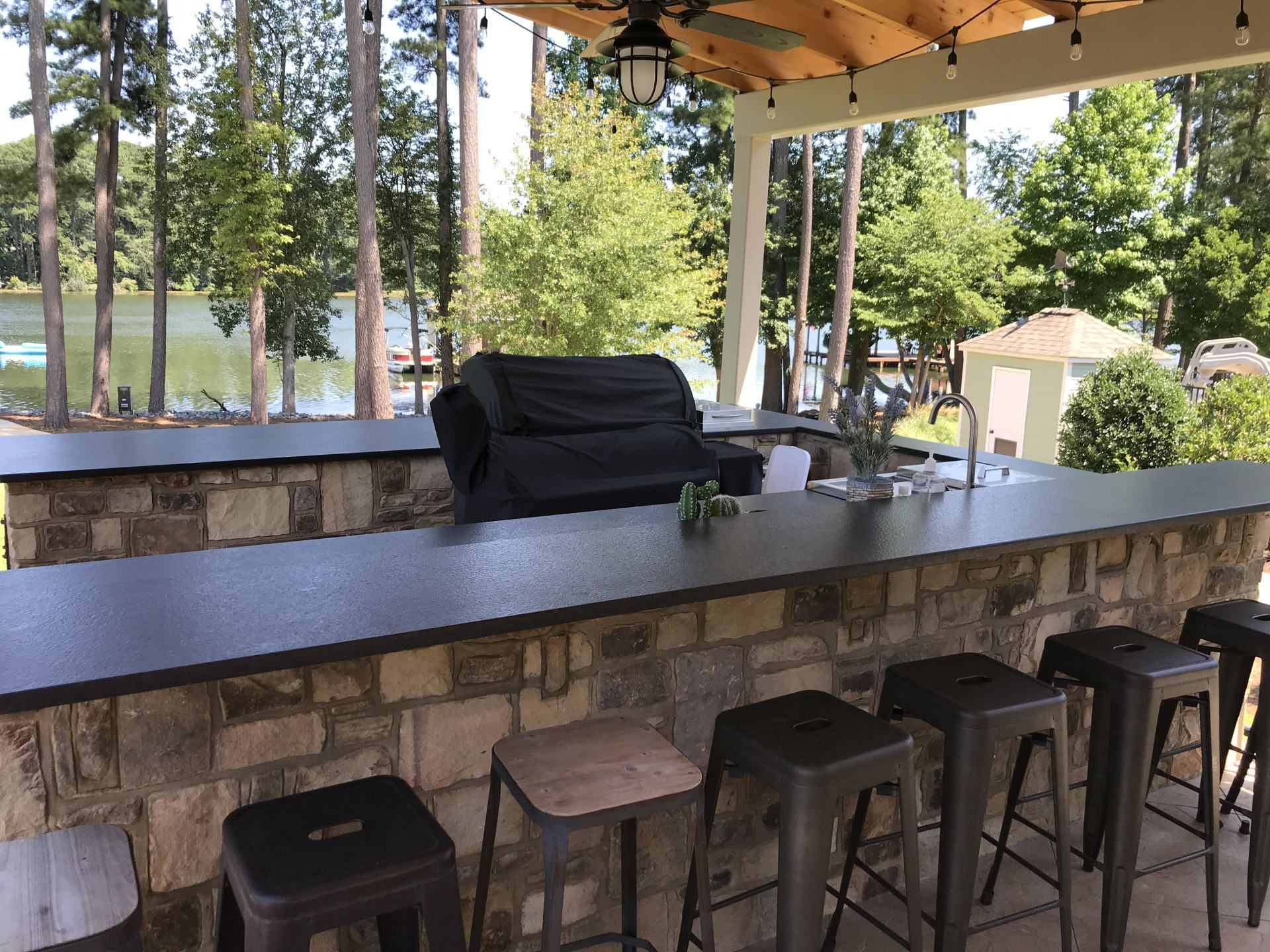 A bar with stools , a grill and a view of a lake.