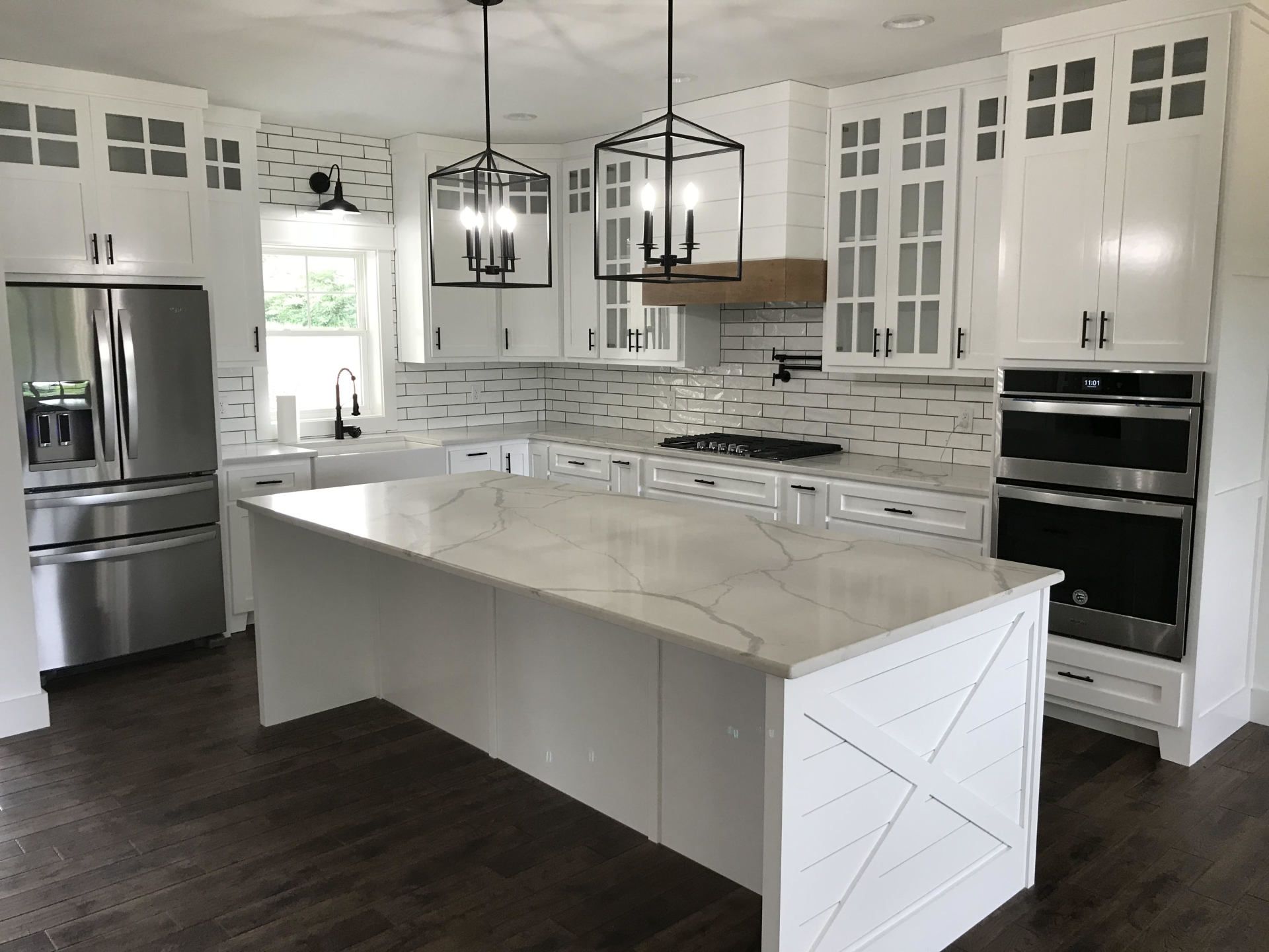A kitchen with white cabinets , stainless steel appliances , and a large island.
