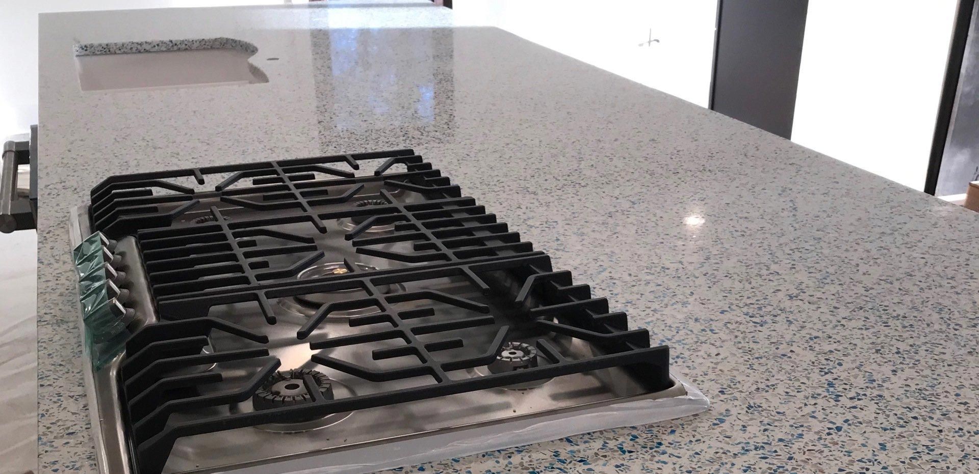 A stove top oven is sitting on top of a granite counter top.