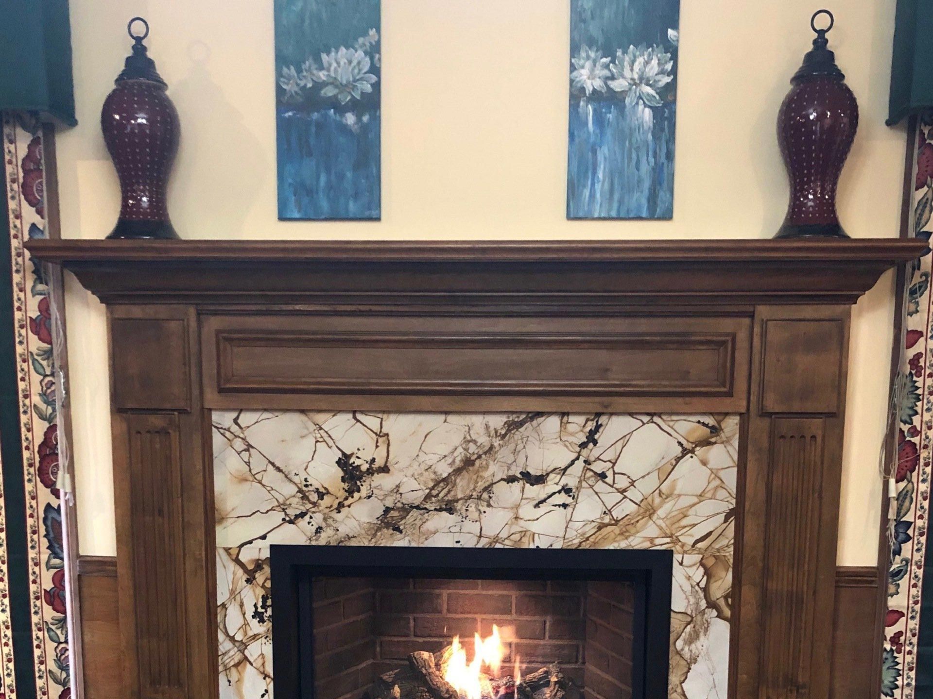A fireplace with a marble tile surround and a wooden mantle