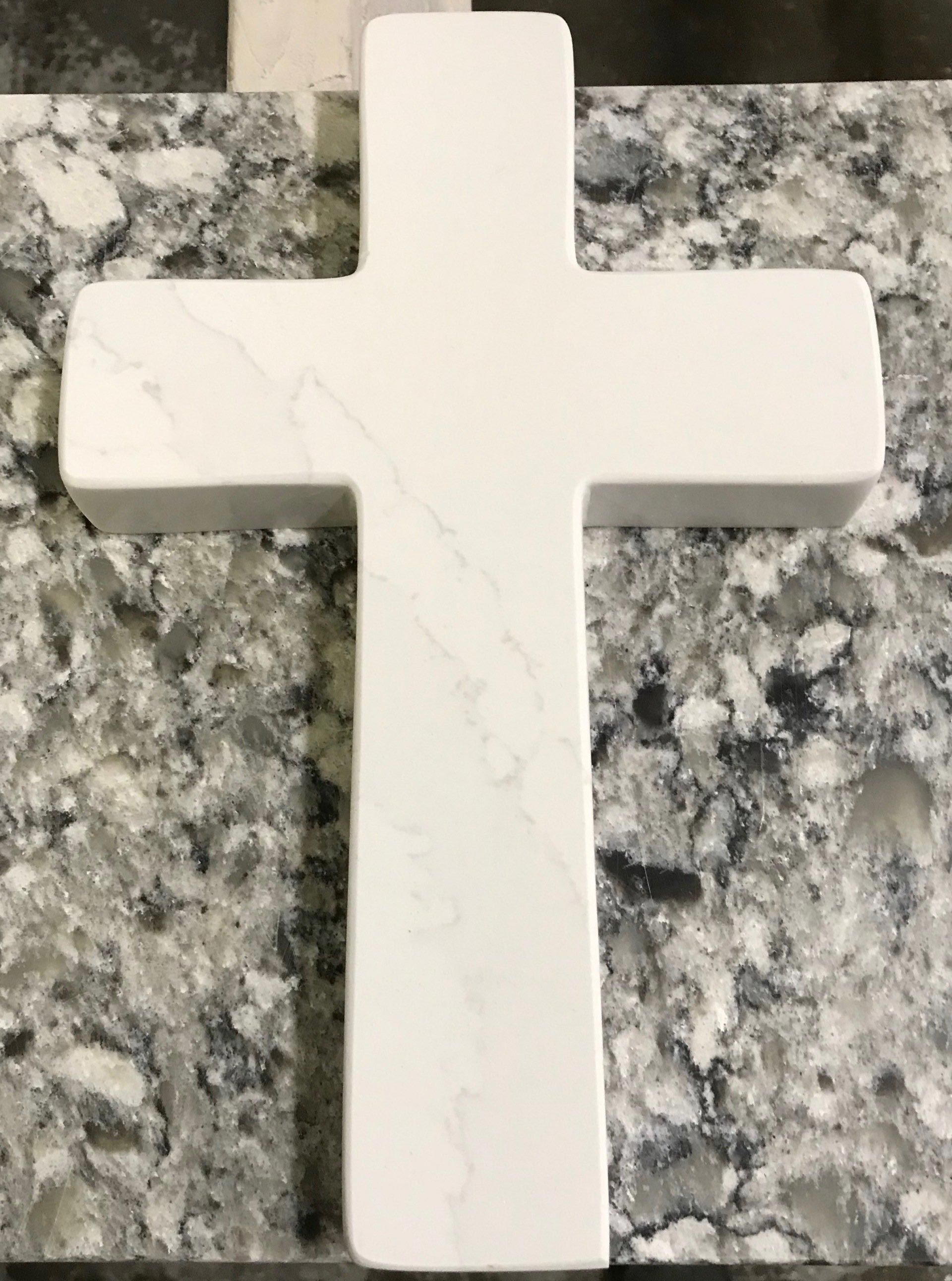 A white cross is sitting on top of a marble counter.