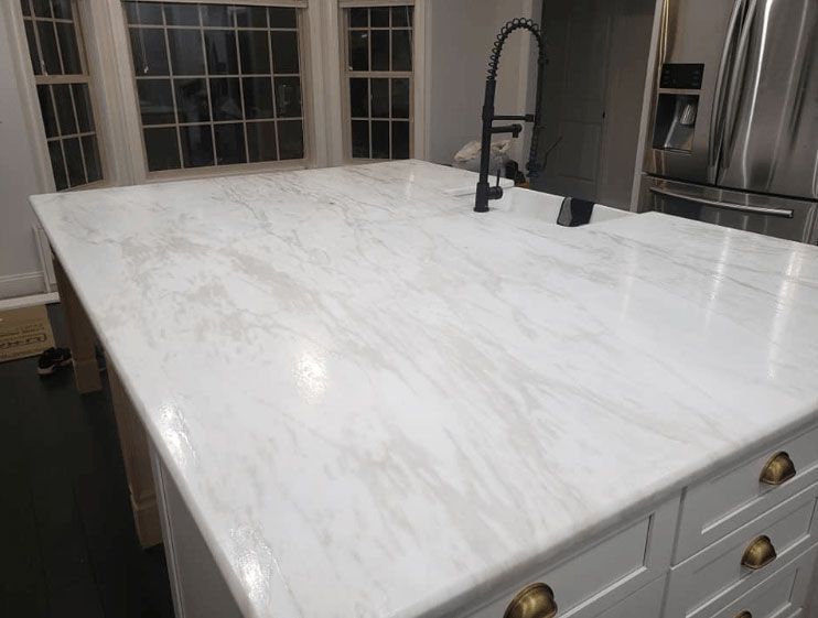 A kitchen with a large white counter top and a sink.