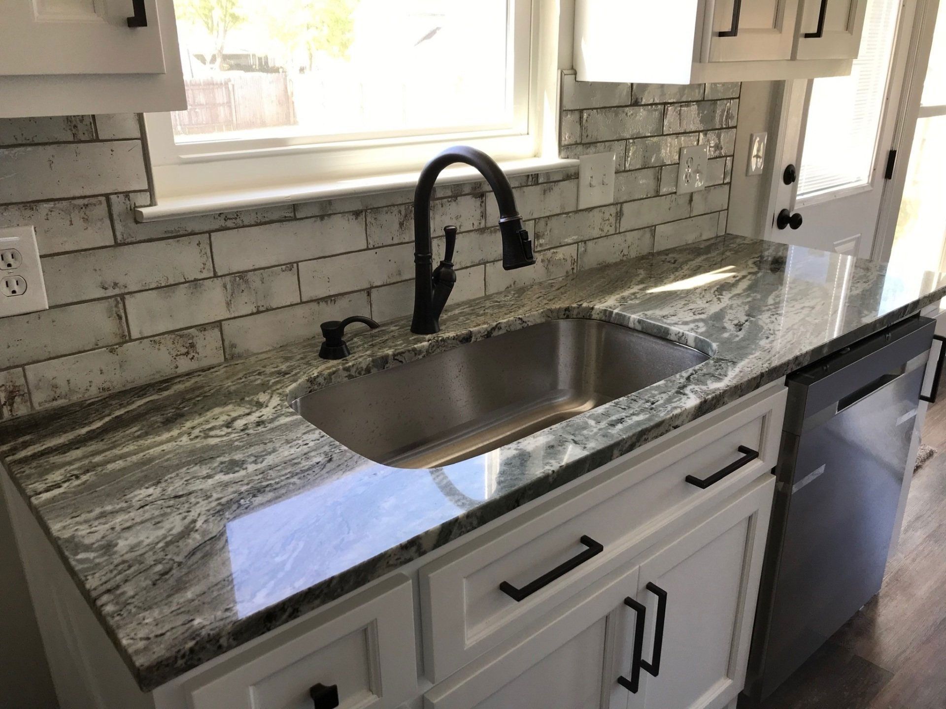 A kitchen with a stainless steel sink and granite counter tops.