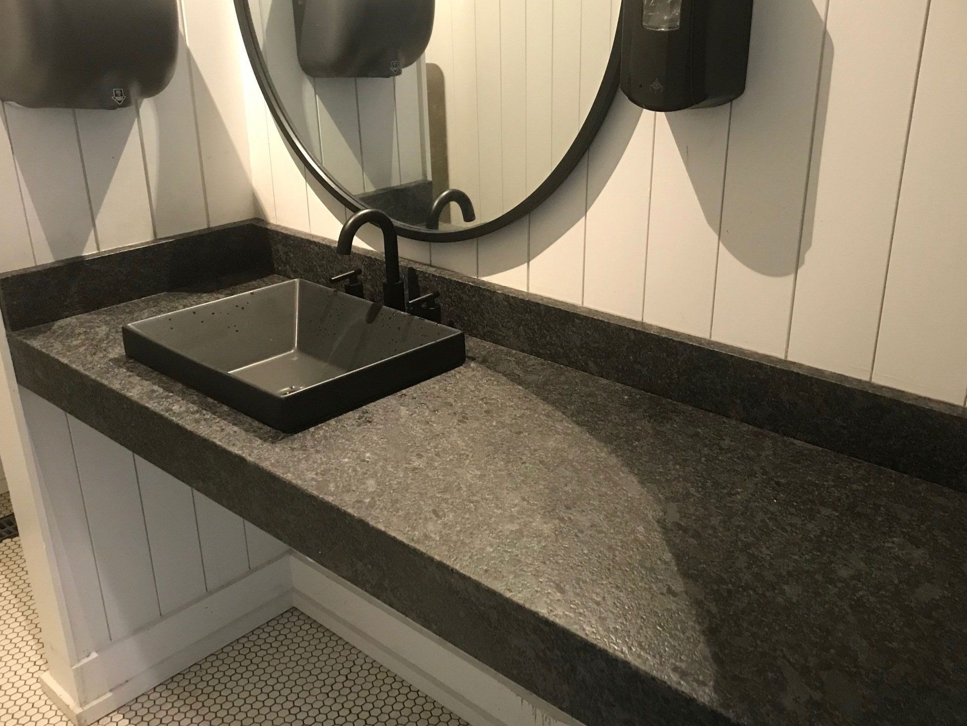 A bathroom with a black sink and a round mirror