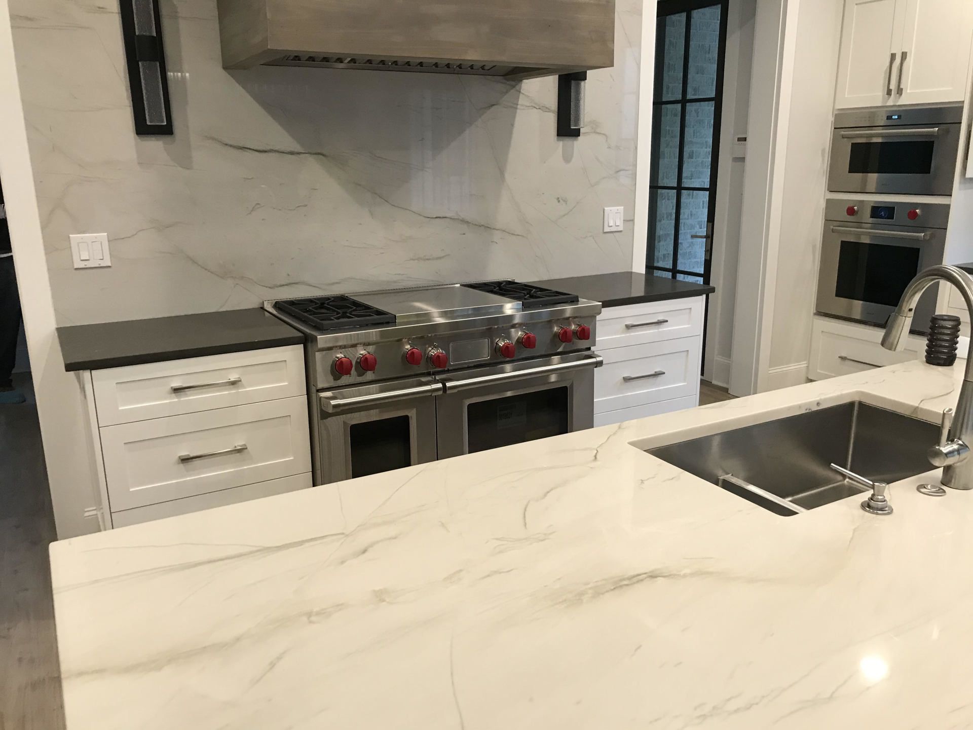 A kitchen with a stove , sink , and oven.