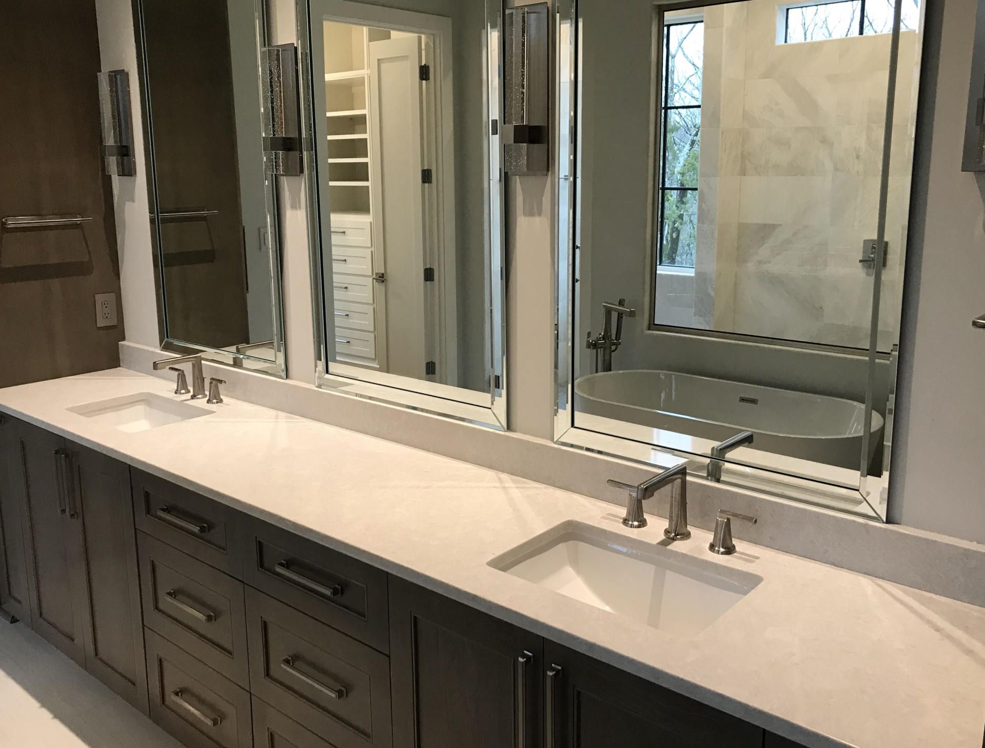 A bathroom with two sinks , two mirrors and a bathtub.