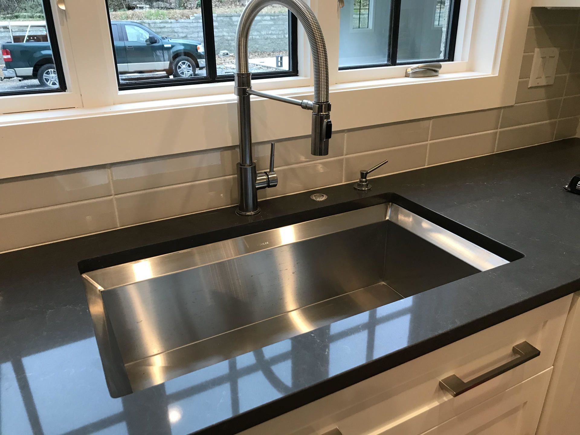 A kitchen sink with a faucet and a window in the background.