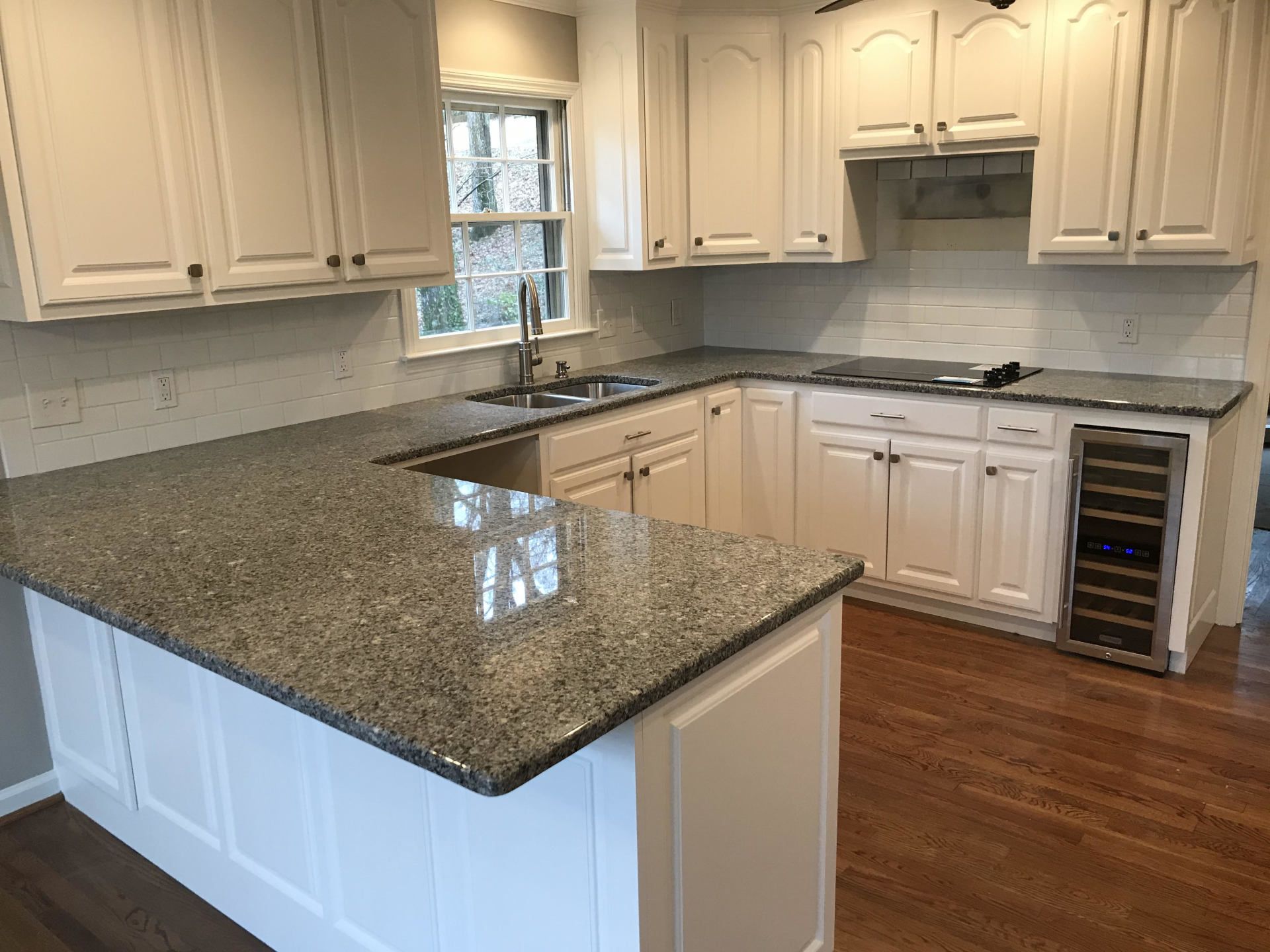 A kitchen with granite counter tops and white cabinets