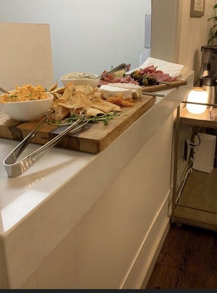 A wooden cutting board with tongs and a bowl of food on it