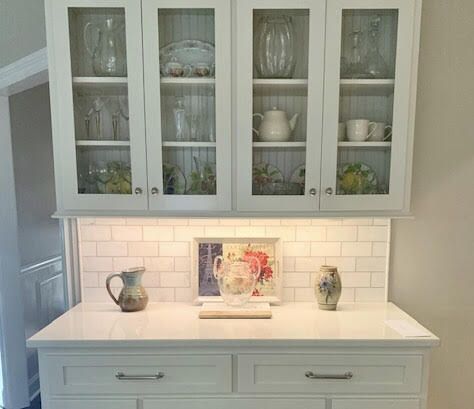 A white cabinet with glass doors and drawers in a kitchen.