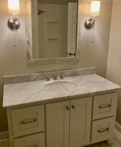 A bathroom with a sink , mirror and light fixtures.