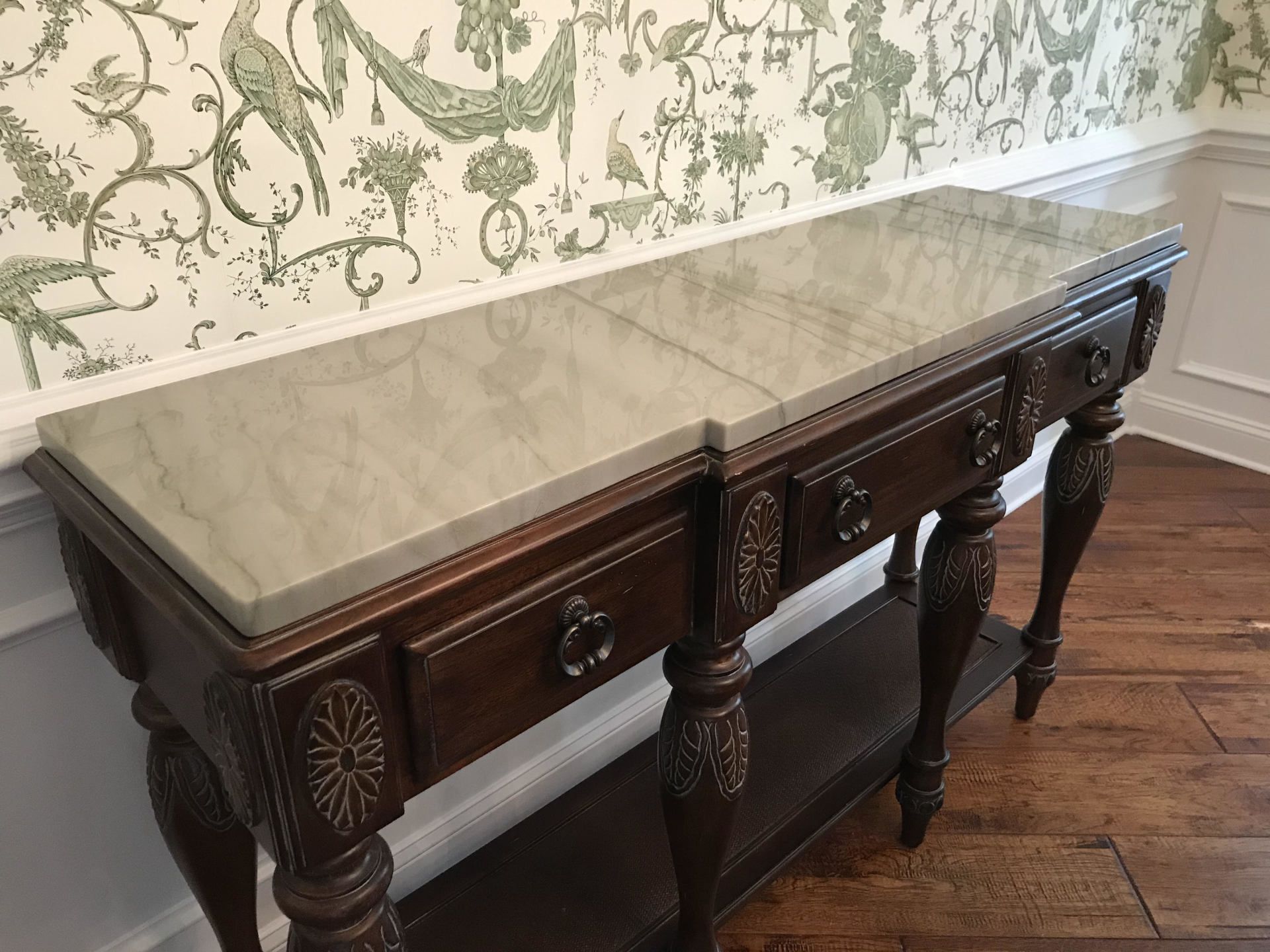 A long wooden table with drawers and a marble top