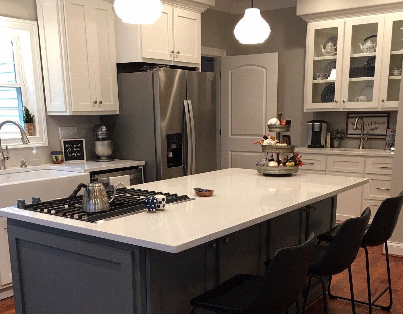 A kitchen with white cabinets , stainless steel appliances , a large island and a stove top oven.