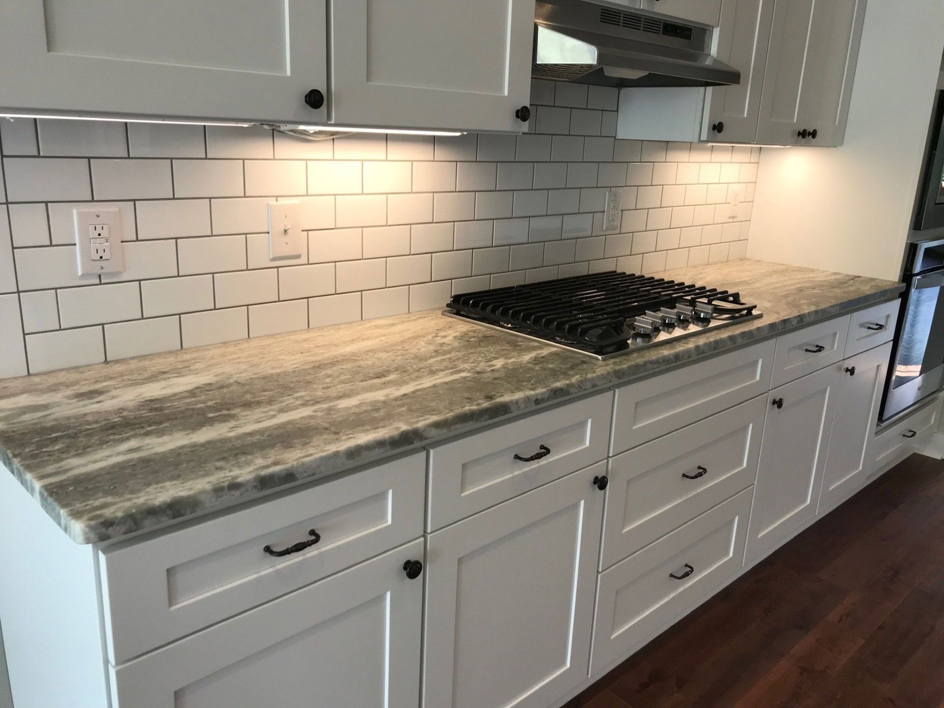 A kitchen with white cabinets and a stove top oven