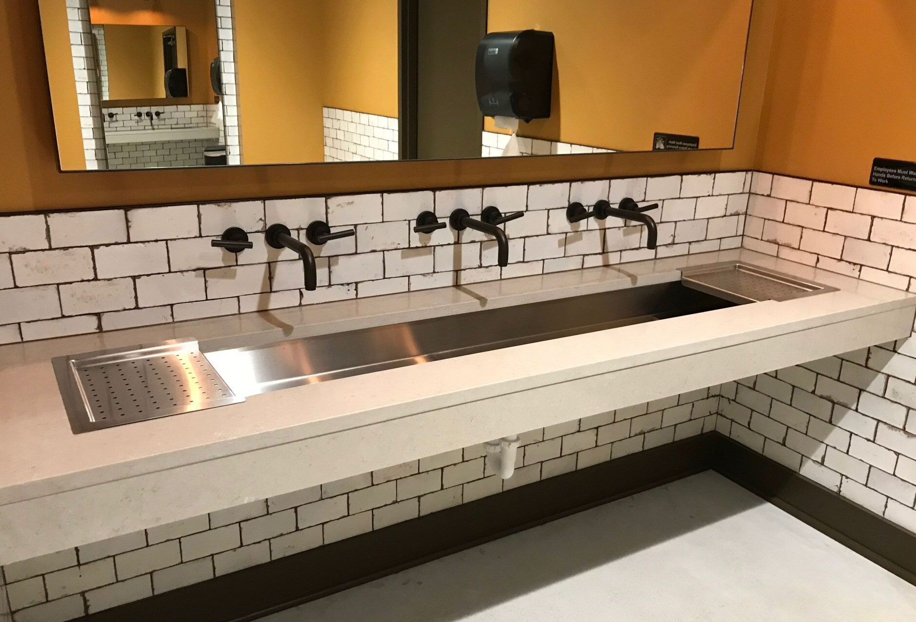 A bathroom with a long sink and a mirror