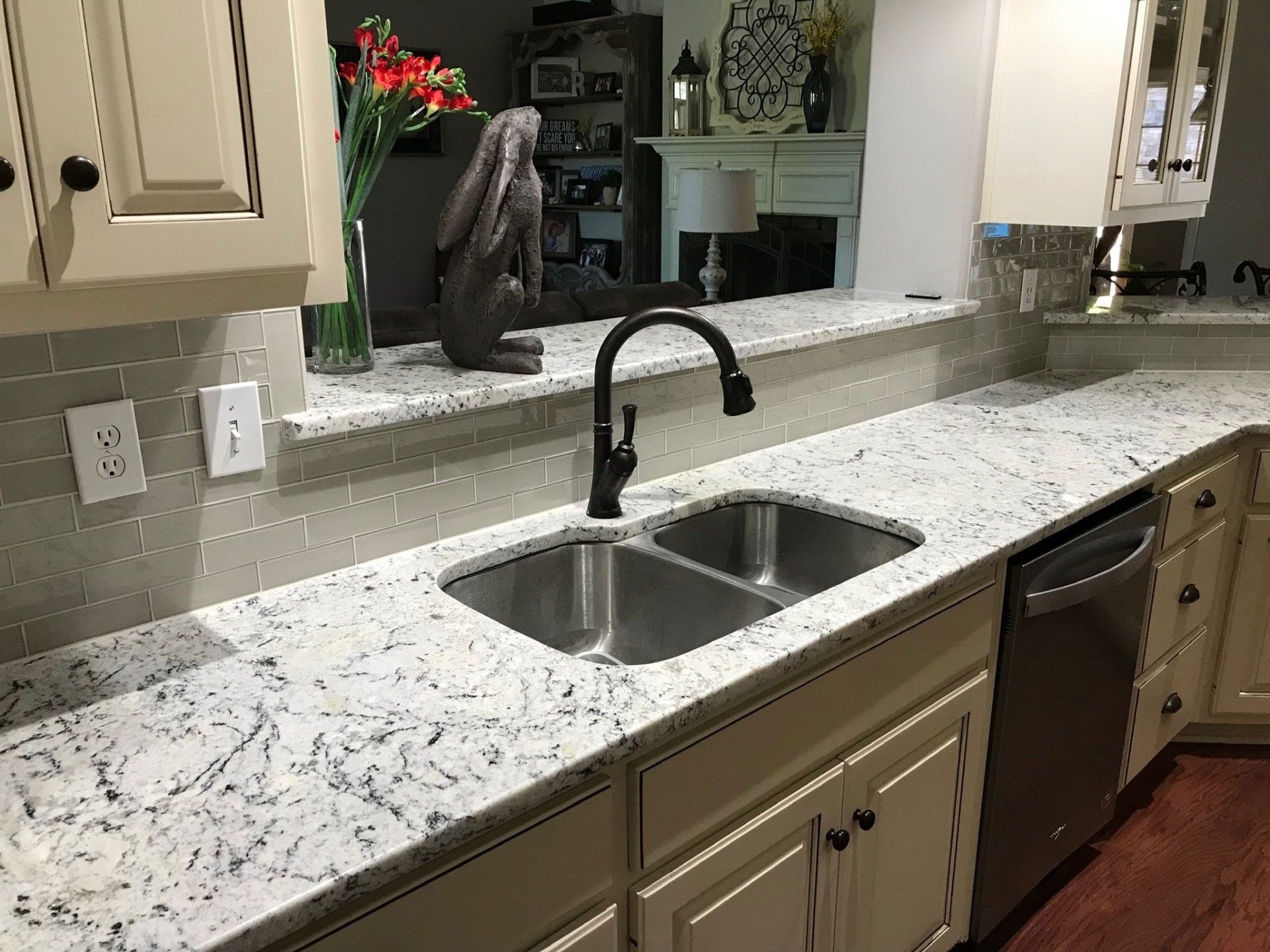 A kitchen with white cabinets , granite counter tops , a sink and a dishwasher.