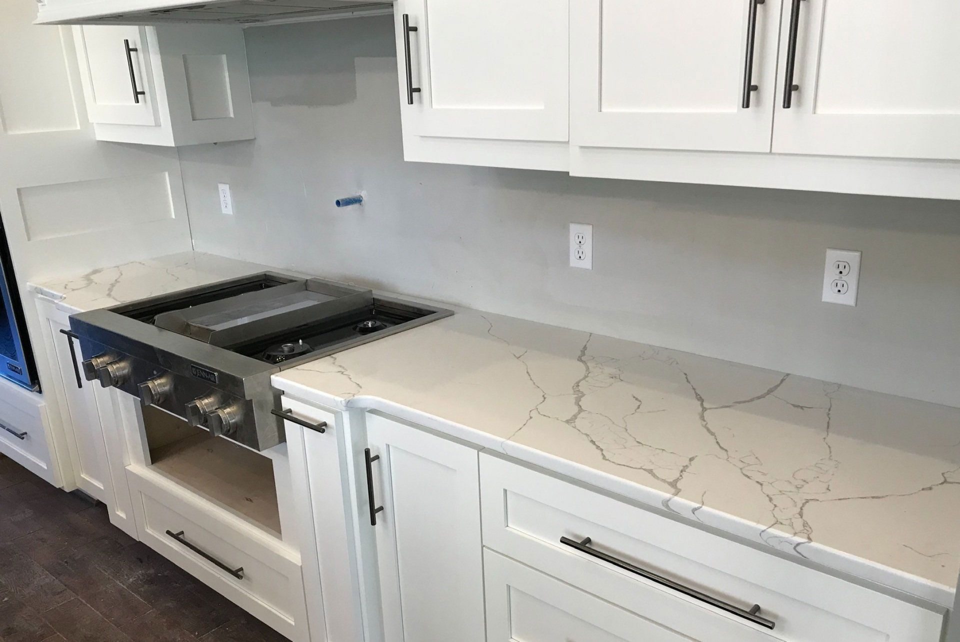 A kitchen with white cabinets and a stove top oven.