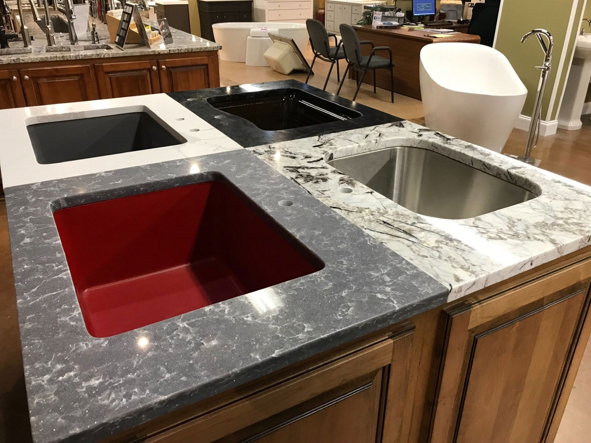 A kitchen counter with a red sink and a stainless steel sink.