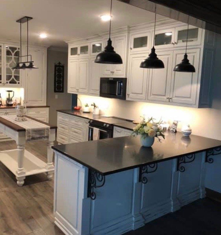 A kitchen with white cabinets and a black counter top