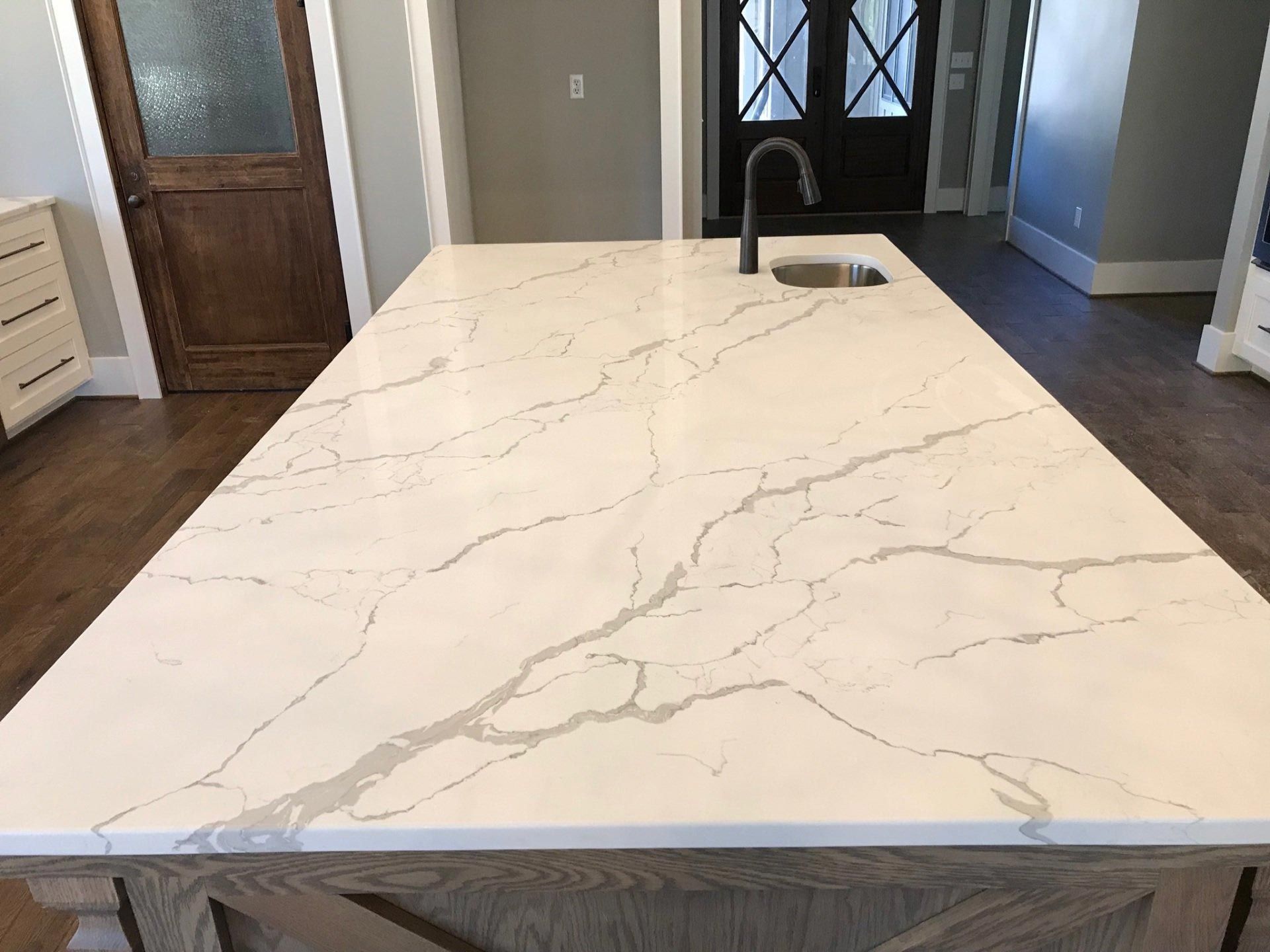 A kitchen island with a marble counter top and a sink.
