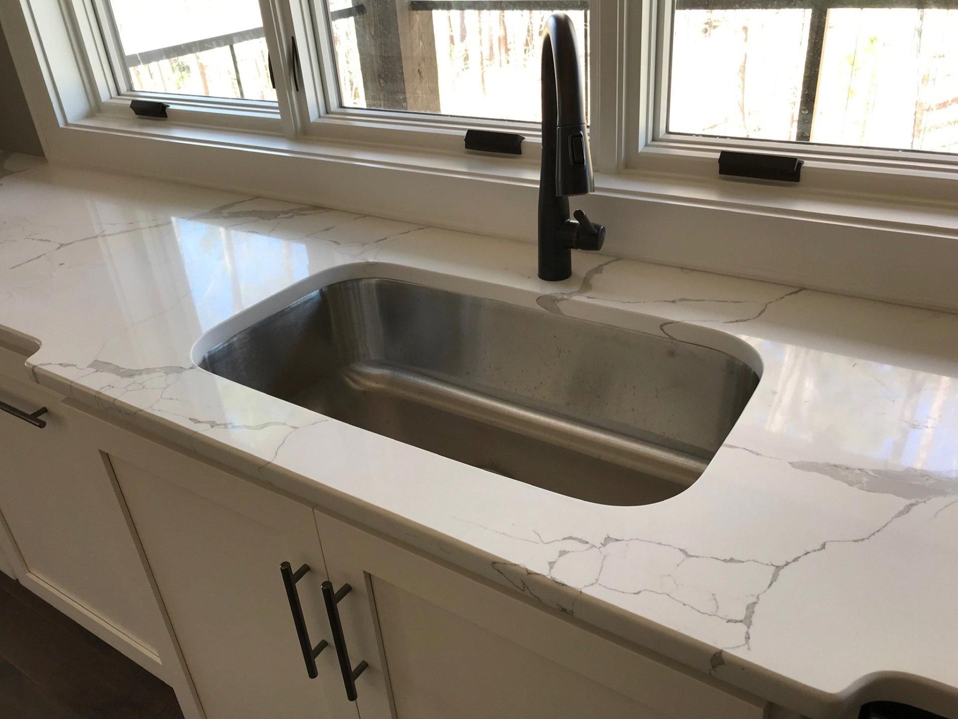 A kitchen sink with a faucet and a window