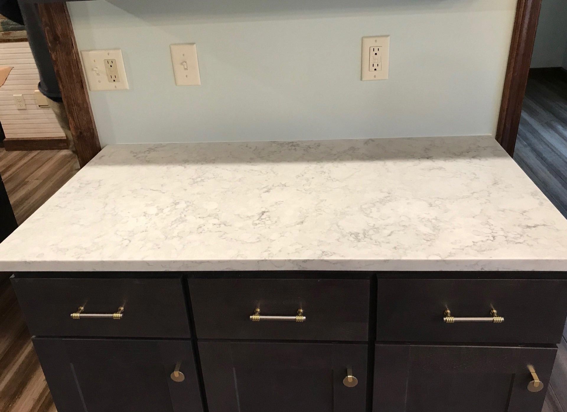 A kitchen counter with a white counter top and black cabinets.