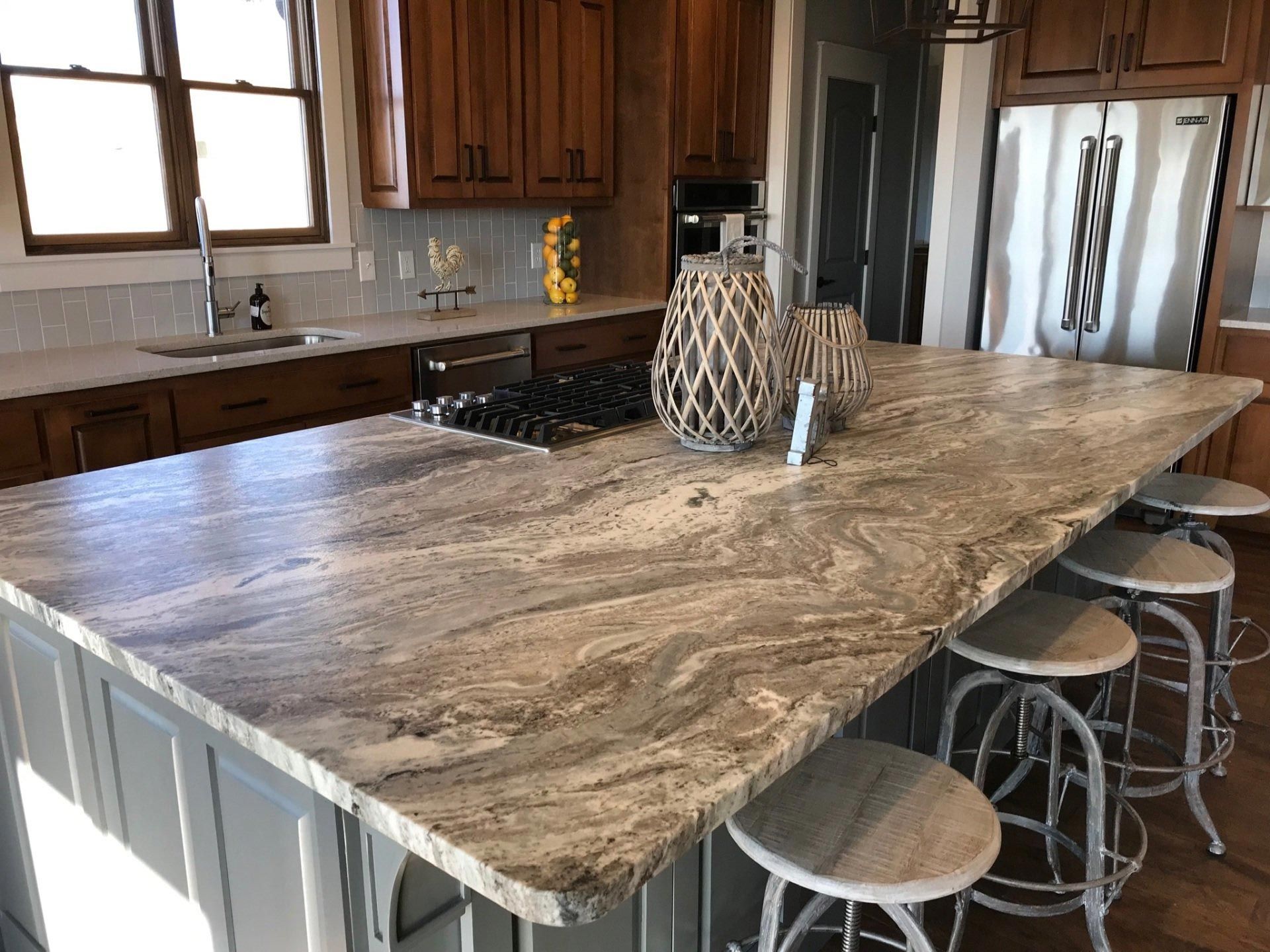 A kitchen with a large granite counter top and stools.
