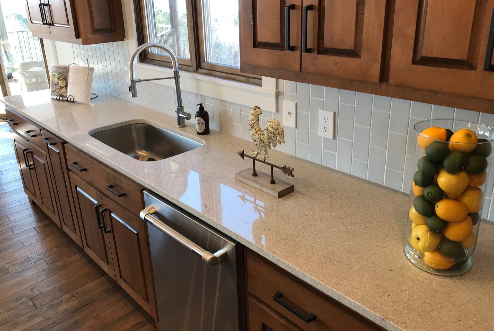 A kitchen with a sink and a bowl of lemons on the counter.