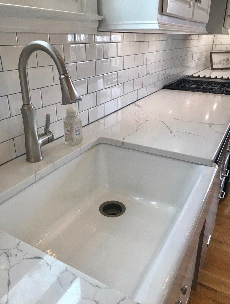 A kitchen sink with a faucet and a soap dispenser on the counter.