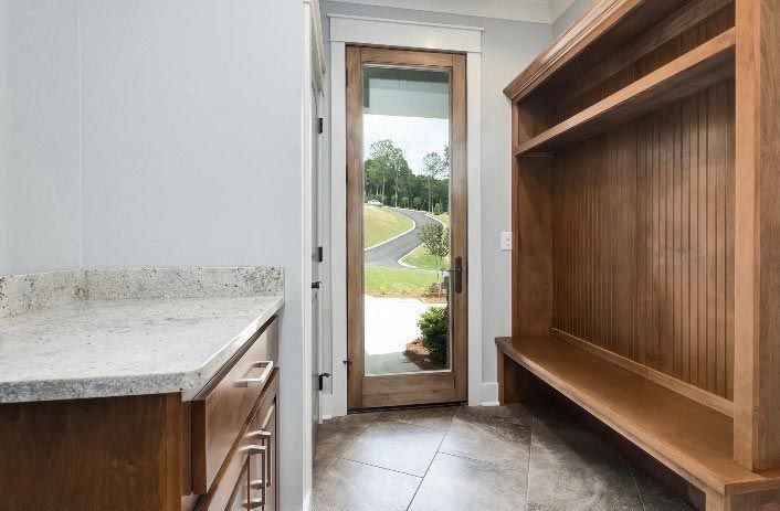 A laundry room with a wooden bench and a glass door.