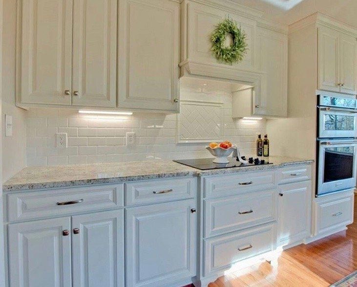 A kitchen with white cabinets , granite counter tops , and stainless steel appliances.
