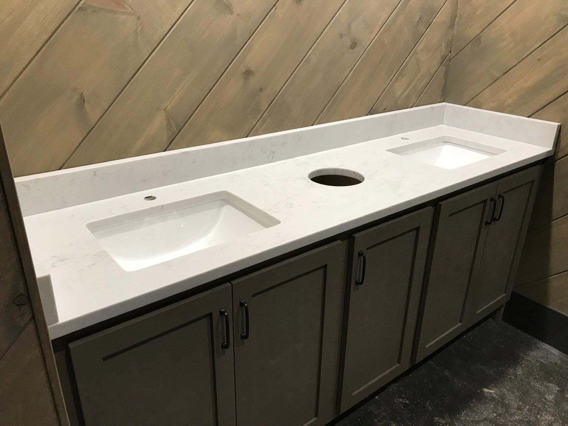 A bathroom with two sinks and a wooden wall.