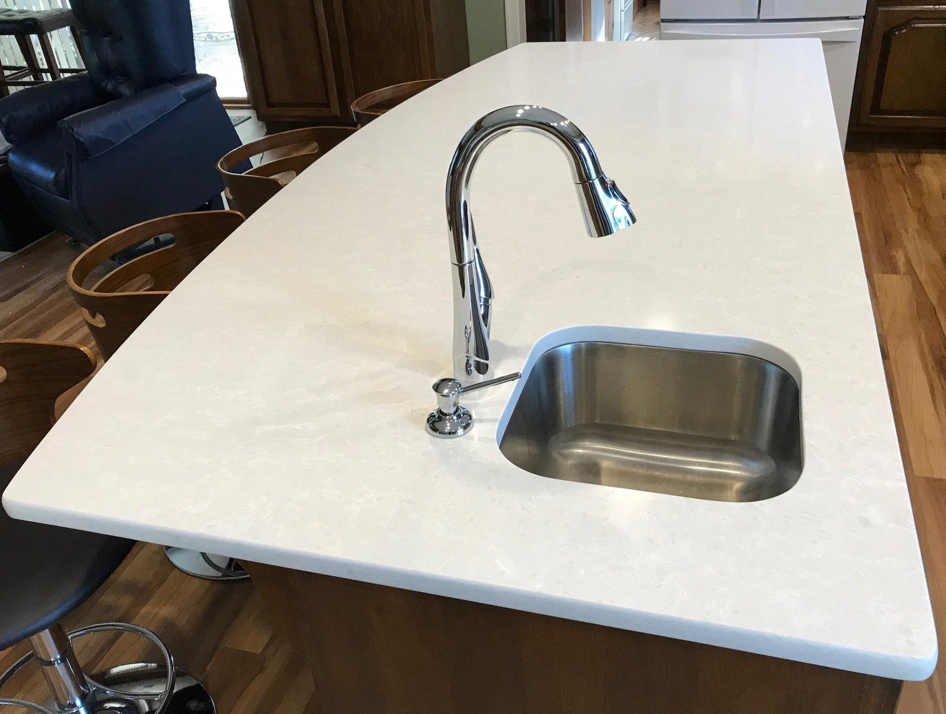 A kitchen island with a stainless steel sink and faucet.