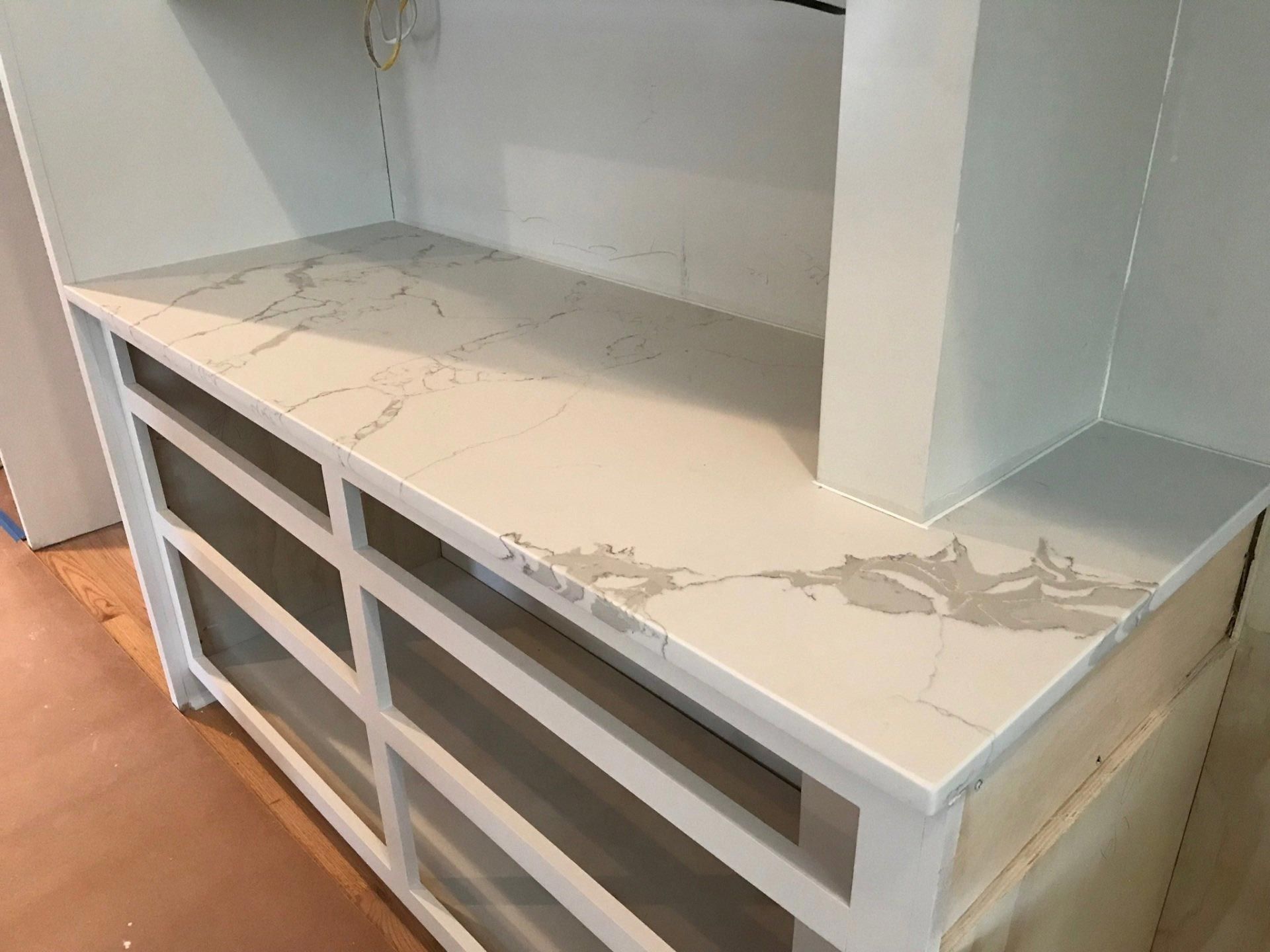 A white cabinet with a marble counter top and drawers.
