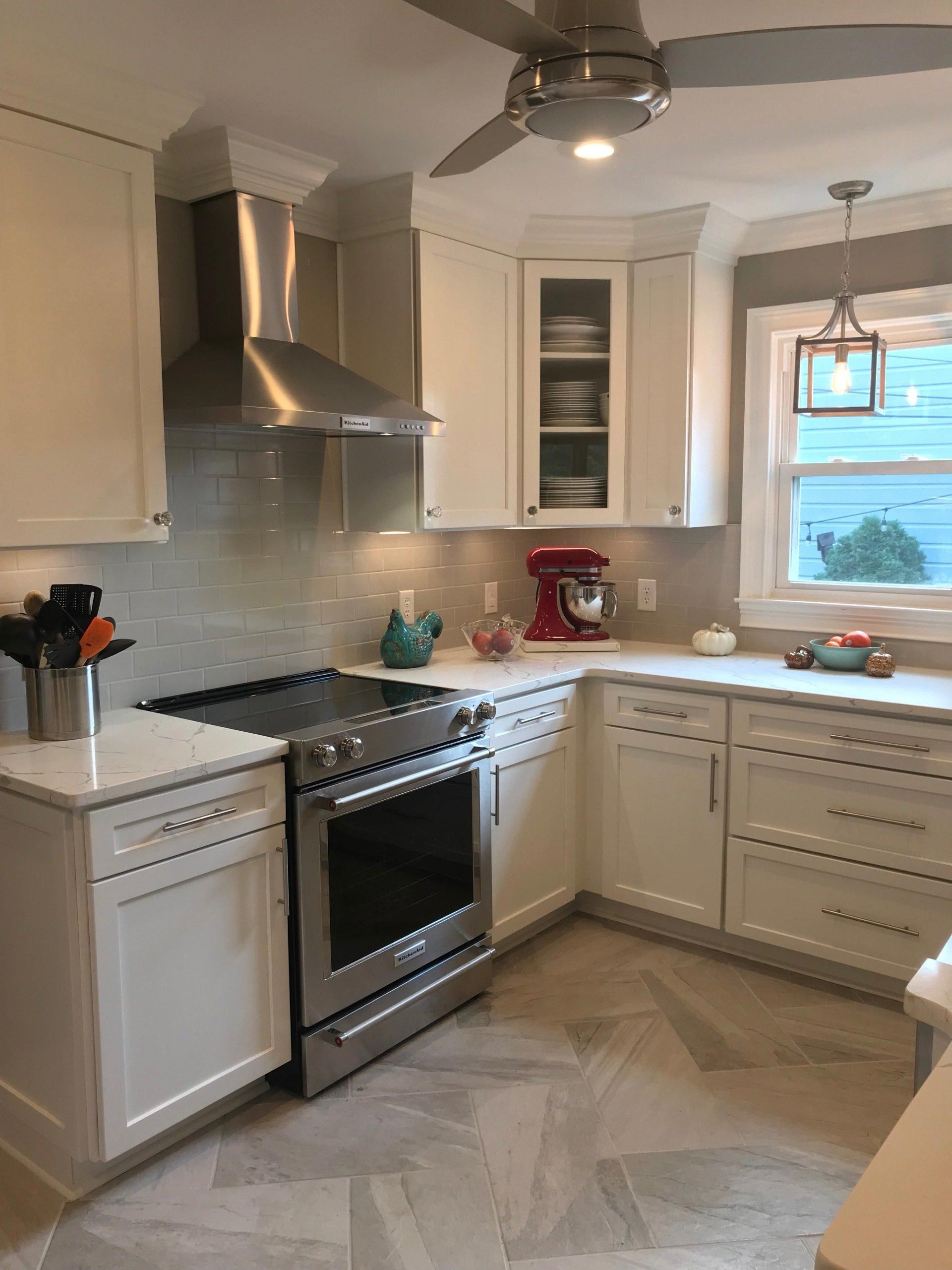 A kitchen with white cabinets , stainless steel appliances and a ceiling fan.