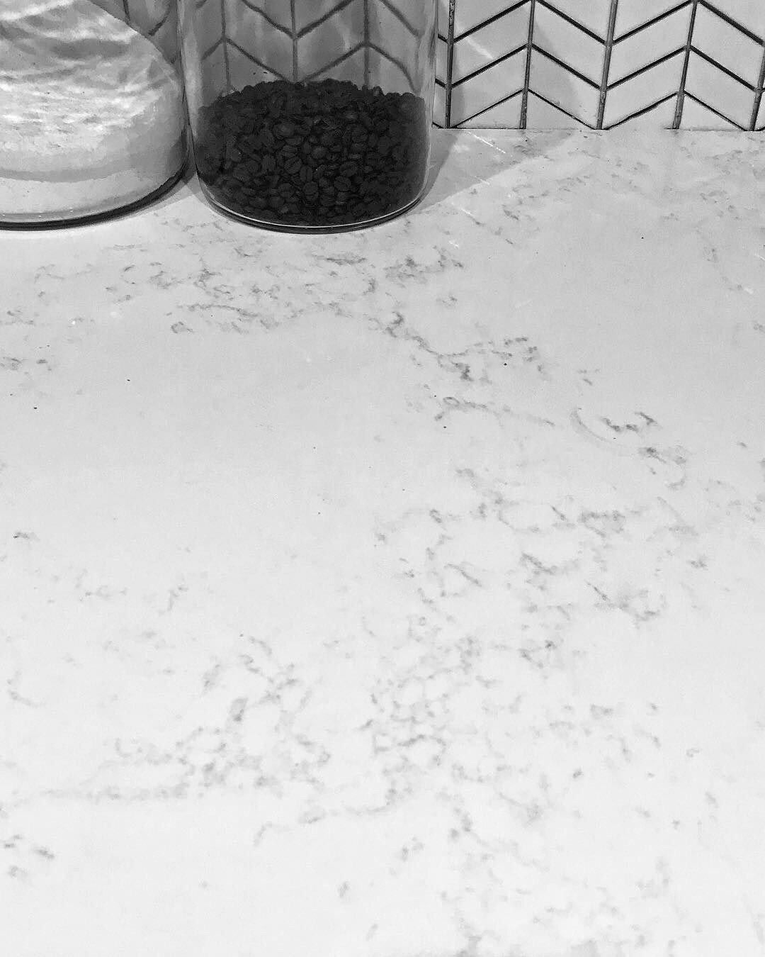 A black and white photo of a counter top with a jar of coffee on it.