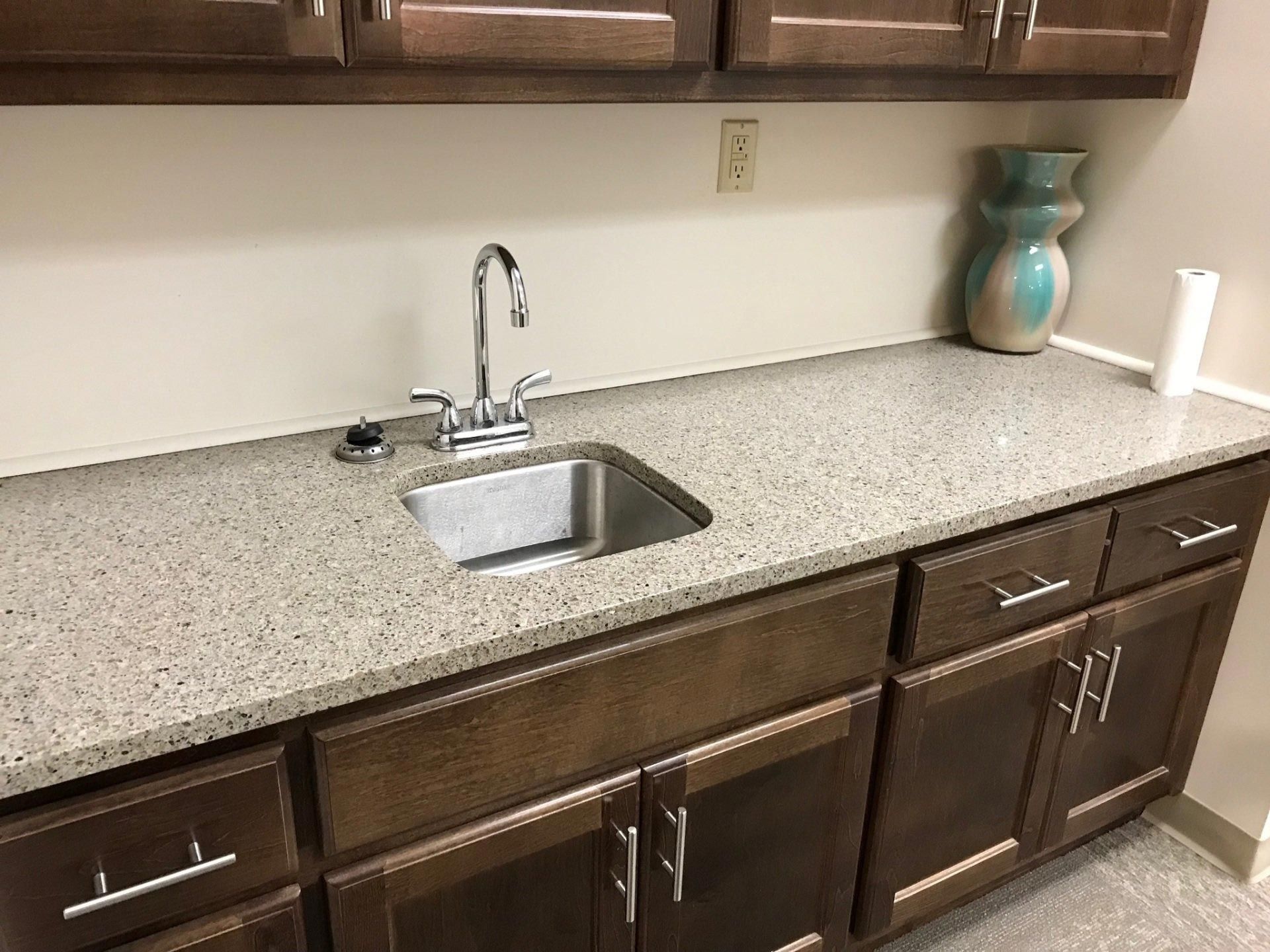 A kitchen with a sink and cabinets and a vase on the counter.
