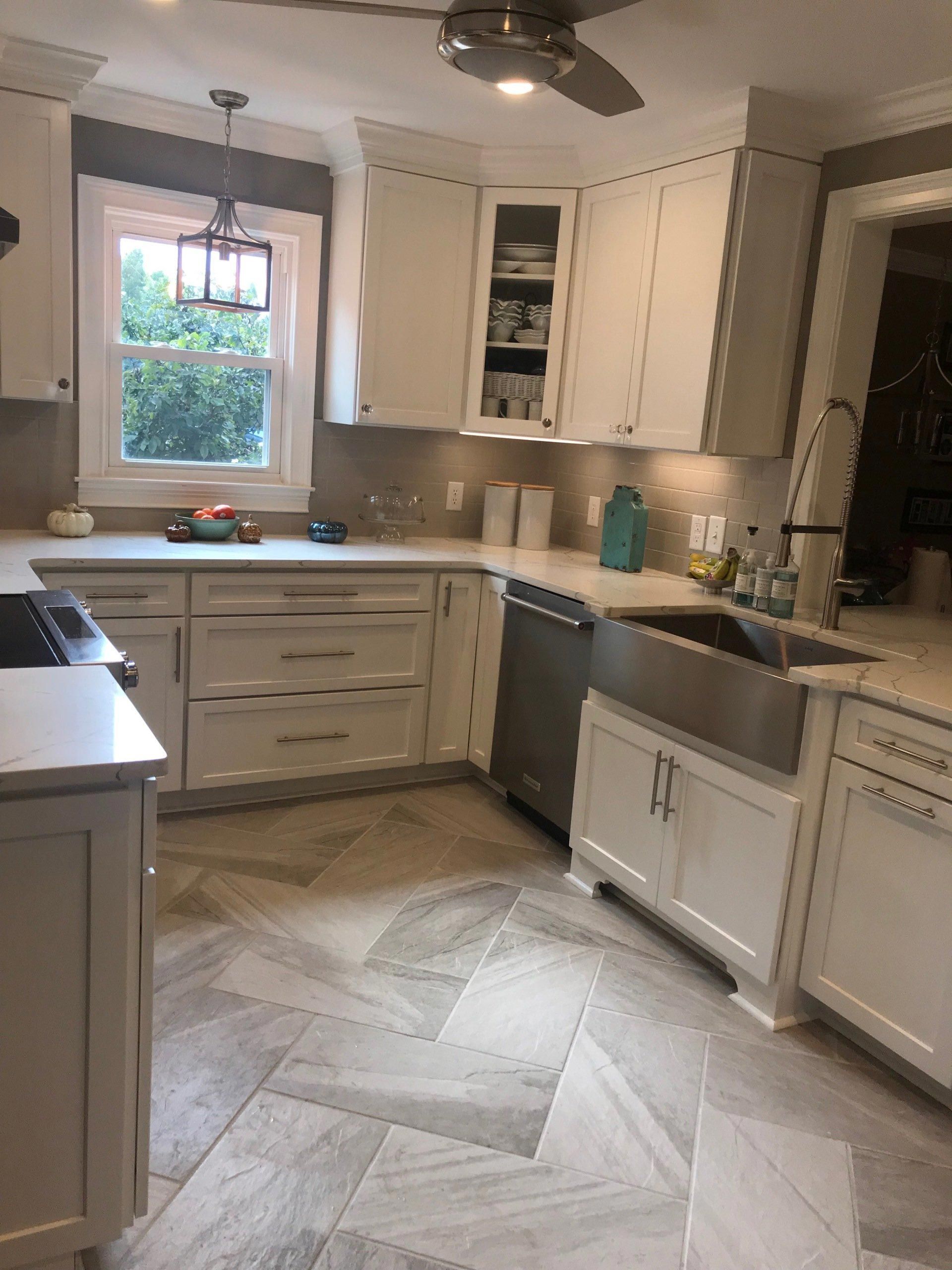 A kitchen with white cabinets , a sink , and a ceiling fan.