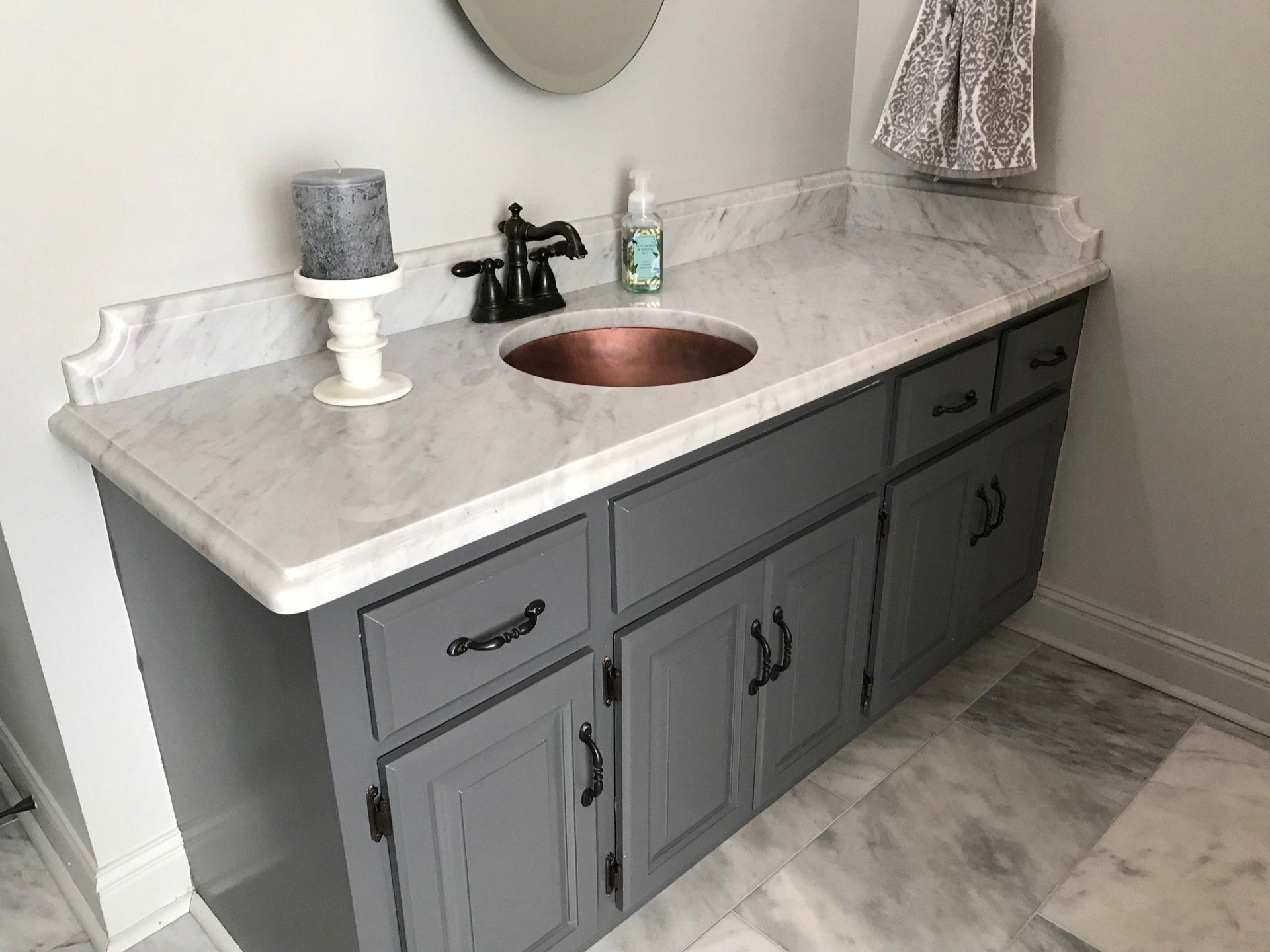 A bathroom vanity with a copper sink and a mirror.