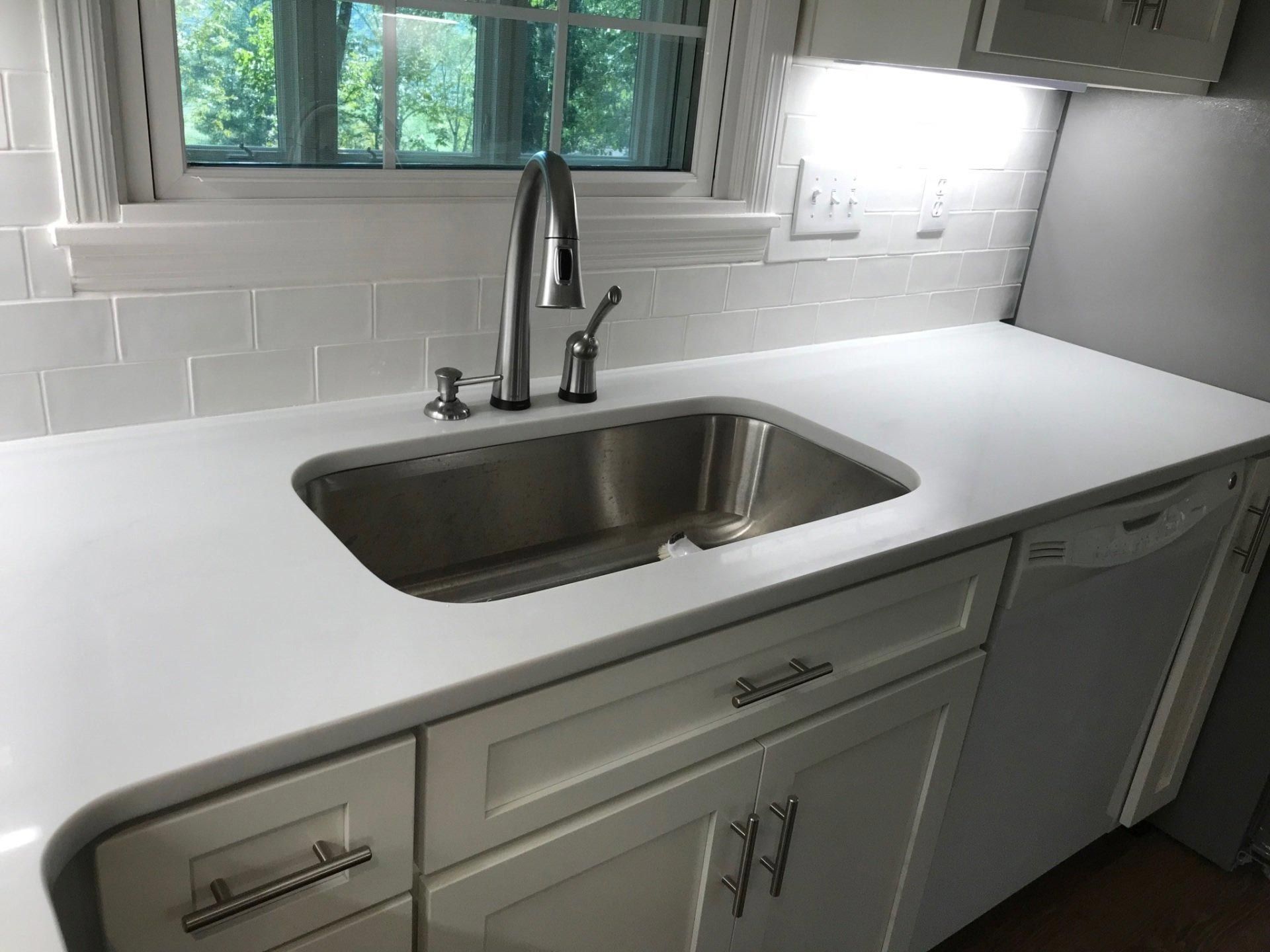 A kitchen with a stainless steel sink and white cabinets