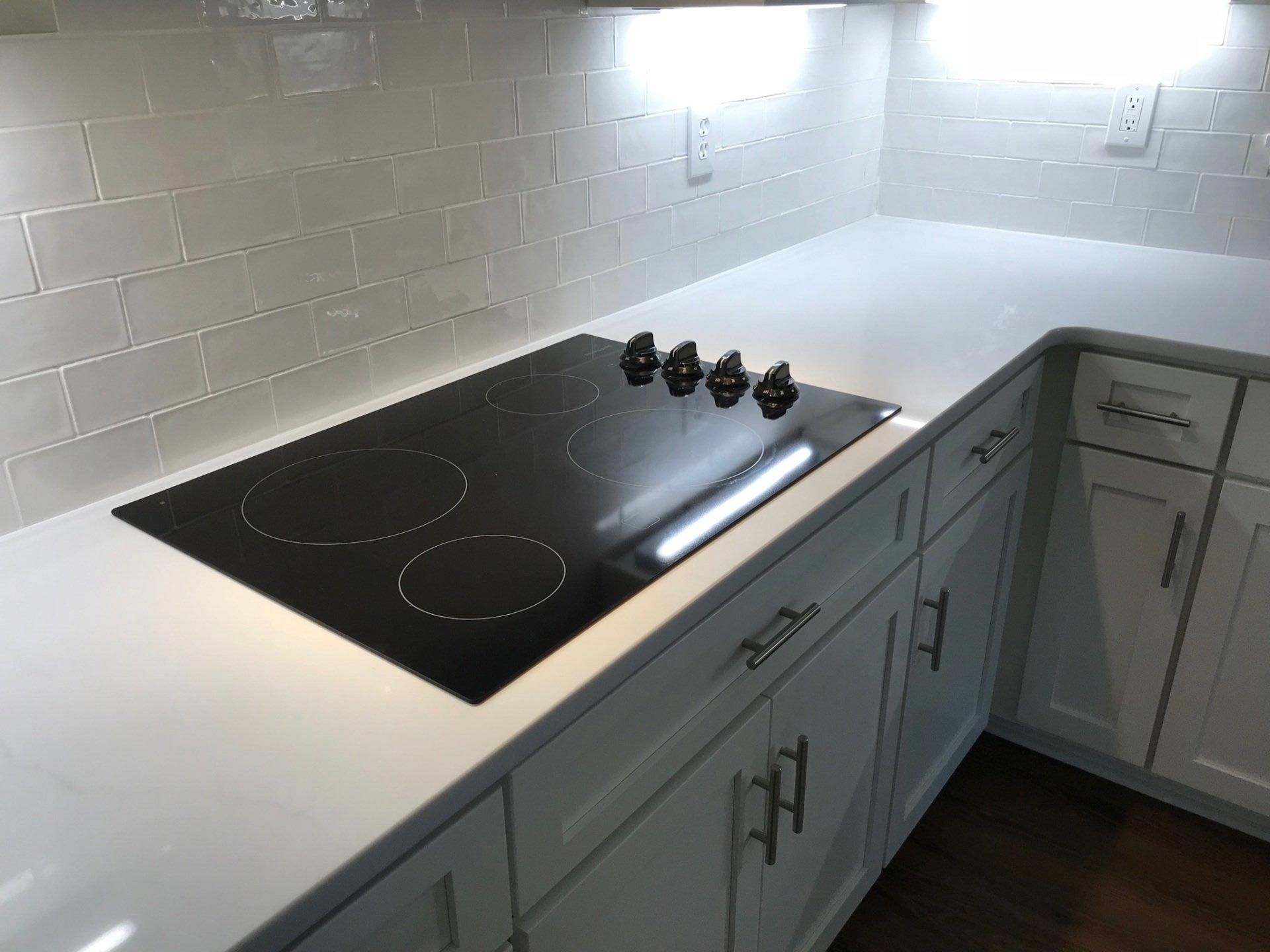A kitchen with white cabinets and a black stove top oven