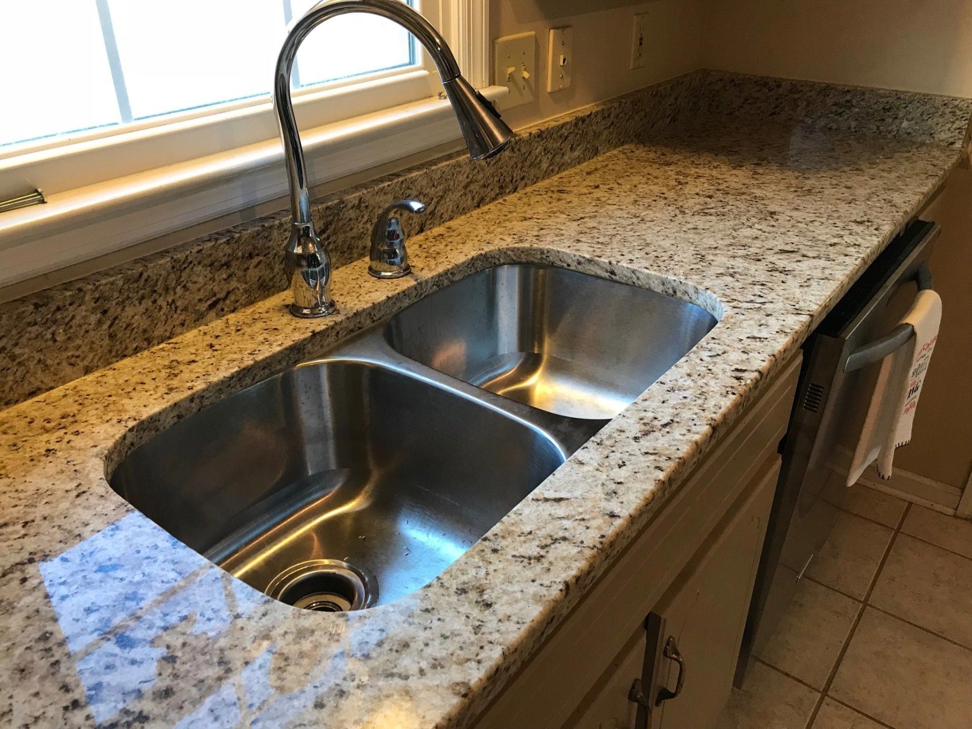 A kitchen sink with a faucet on a granite counter top.