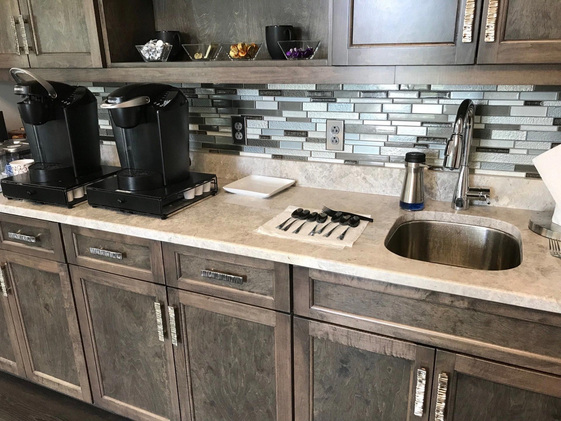 A kitchen with a sink , cabinets , and coffee makers.
