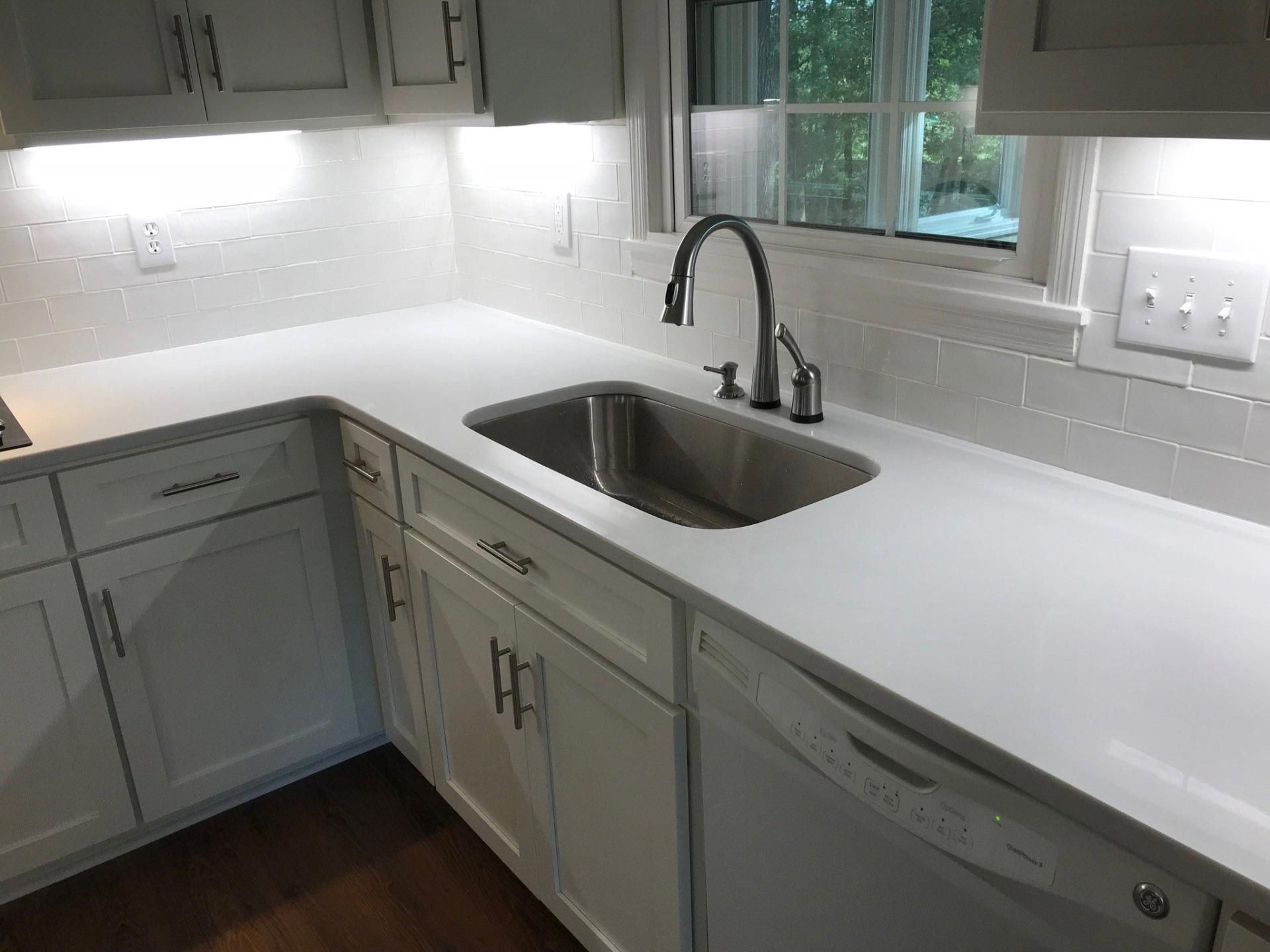 A kitchen with white cabinets and a stainless steel sink