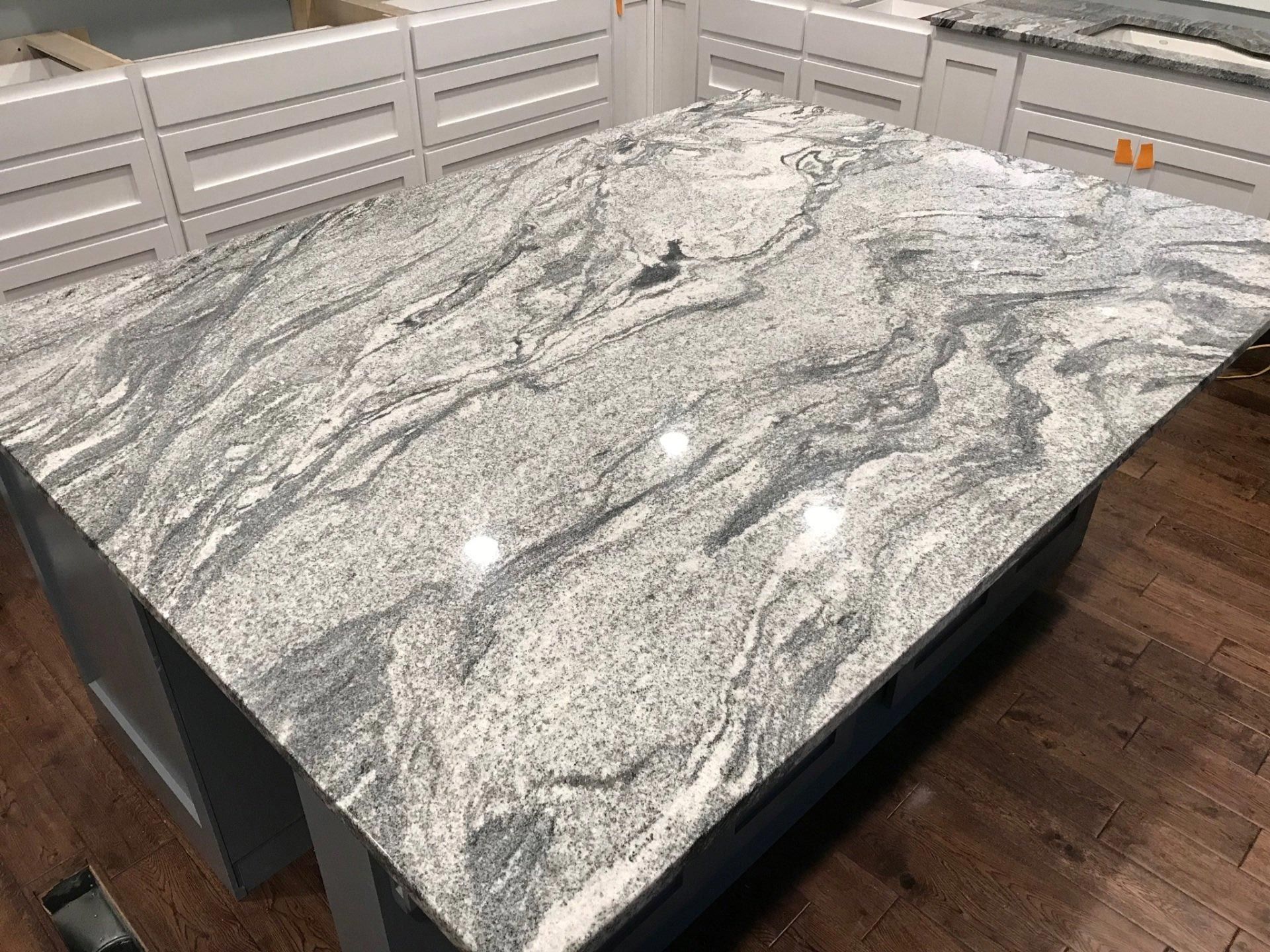 A large granite counter top is sitting on top of a wooden floor in a kitchen.