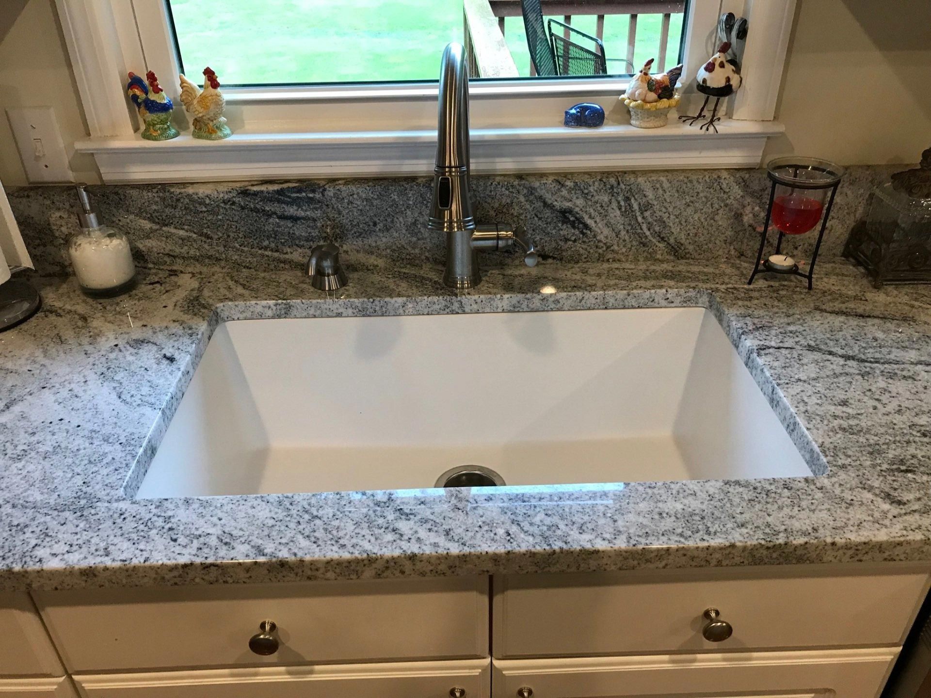 A kitchen sink with a faucet and a window in the background.