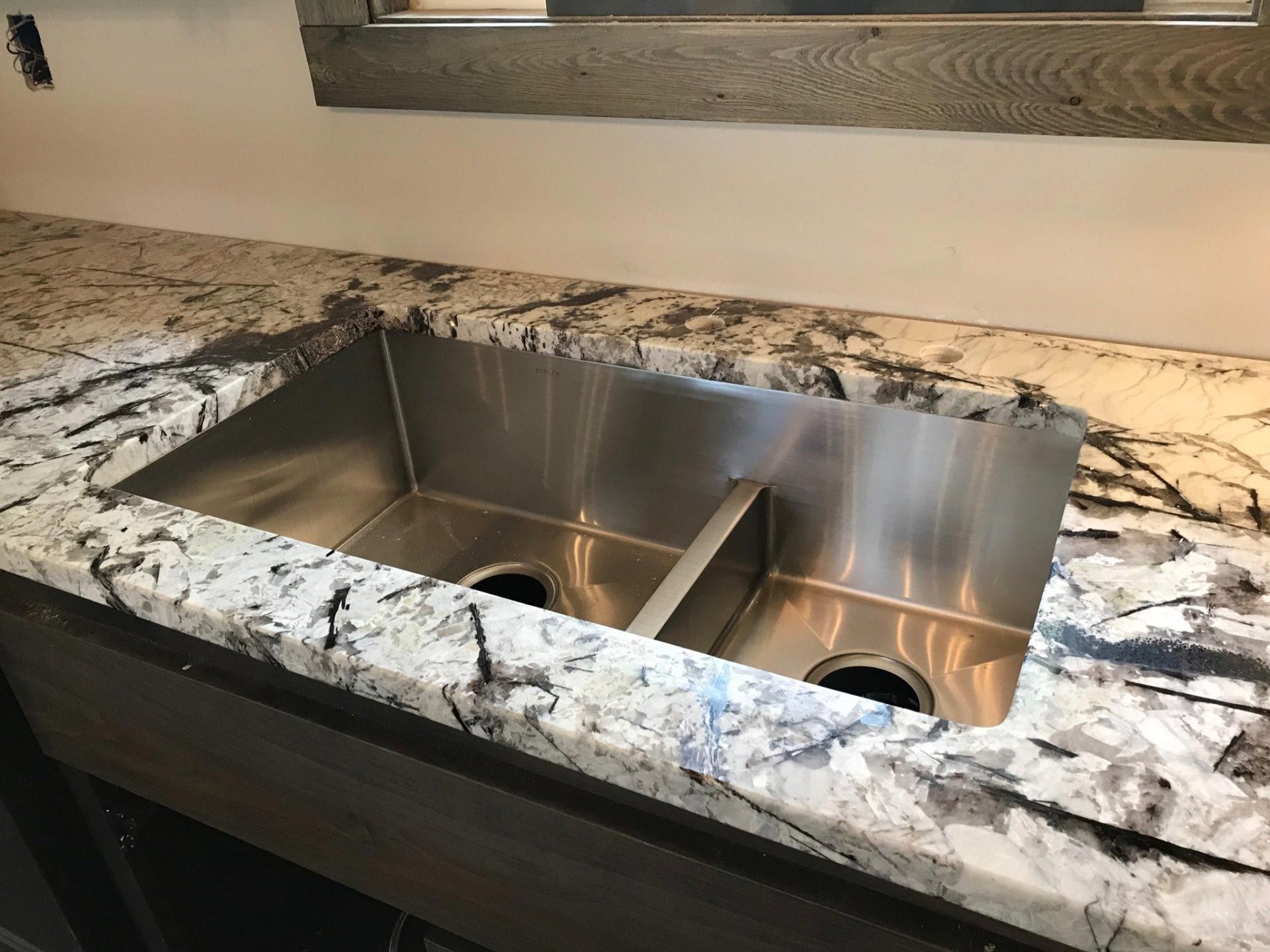 A stainless steel sink is sitting on top of a granite counter.