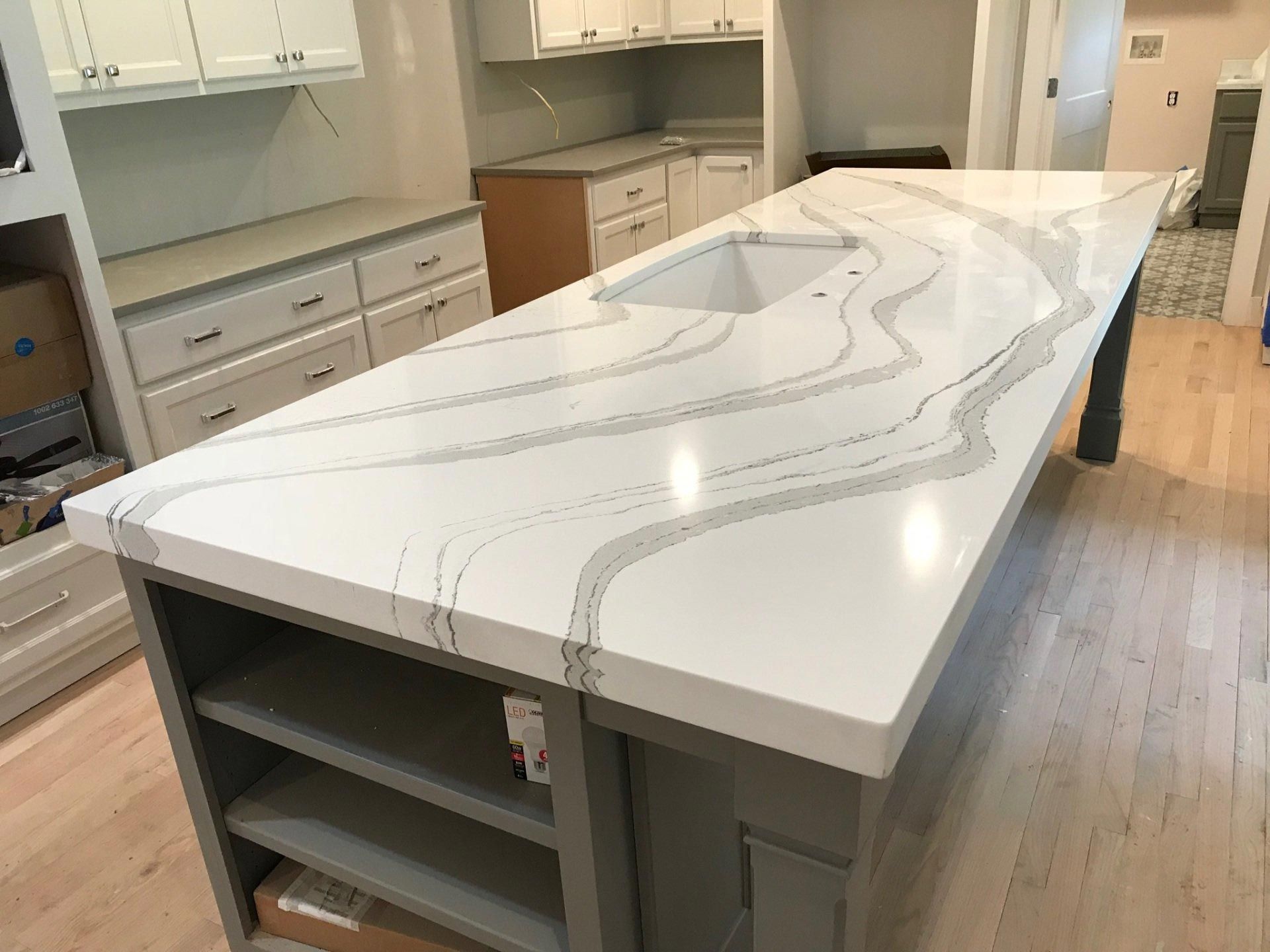 A kitchen with a large white counter top and a sink.