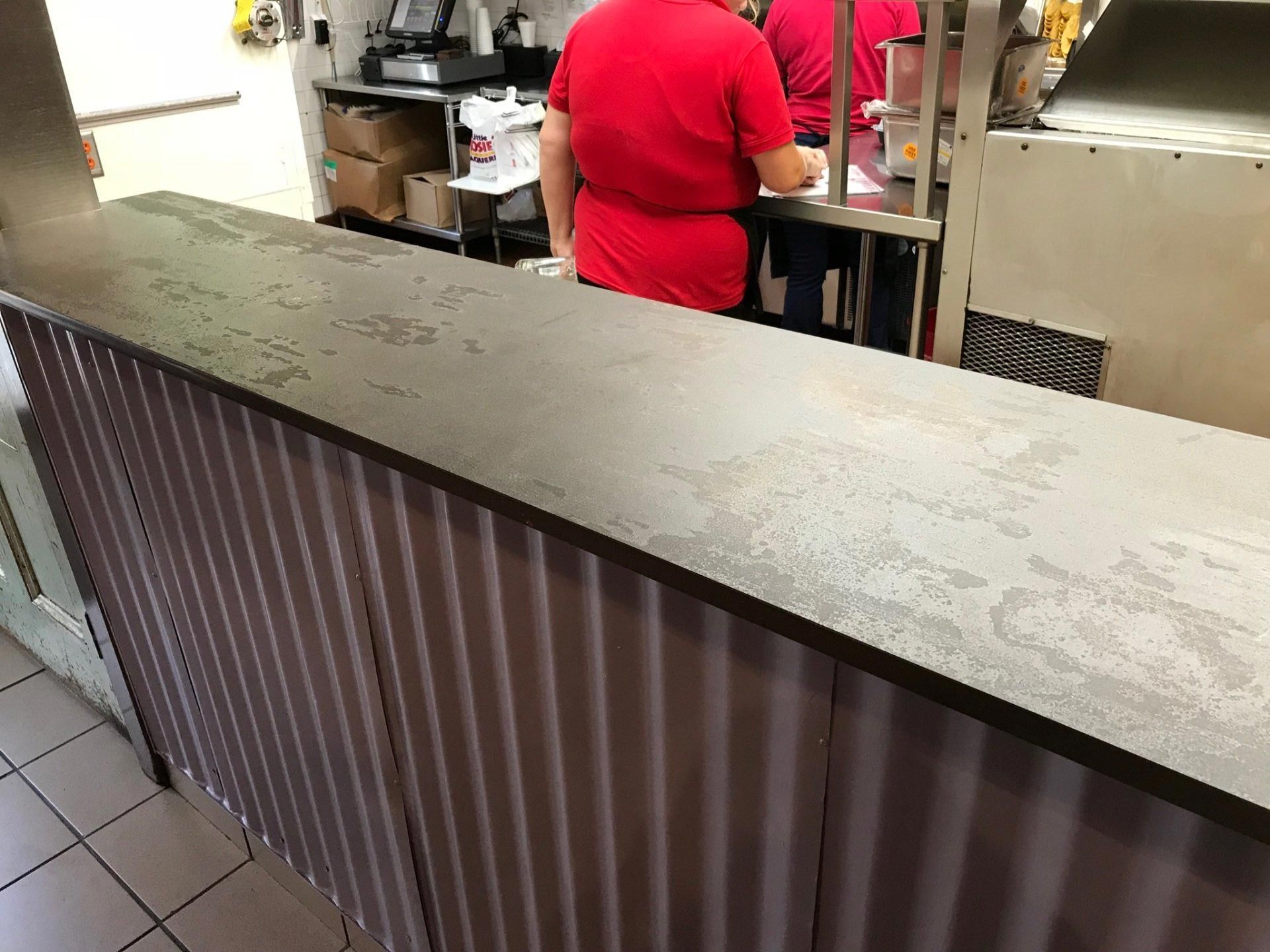 A man in a red shirt is standing behind a counter in a restaurant